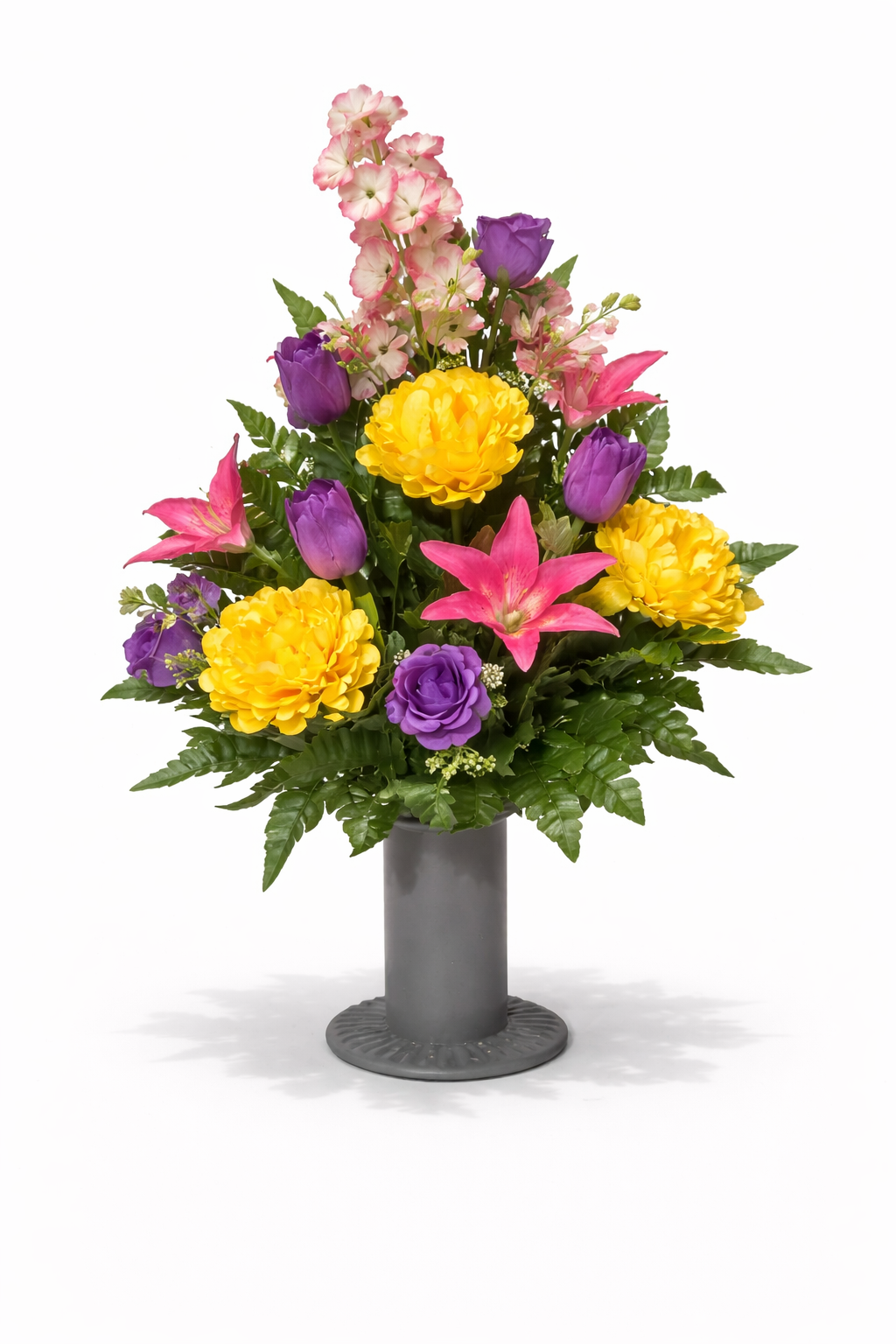 Colorful floral arrangement with pink lilies, yellow peonies, purple tulips, and pink and white stock flowers in a gray vase.