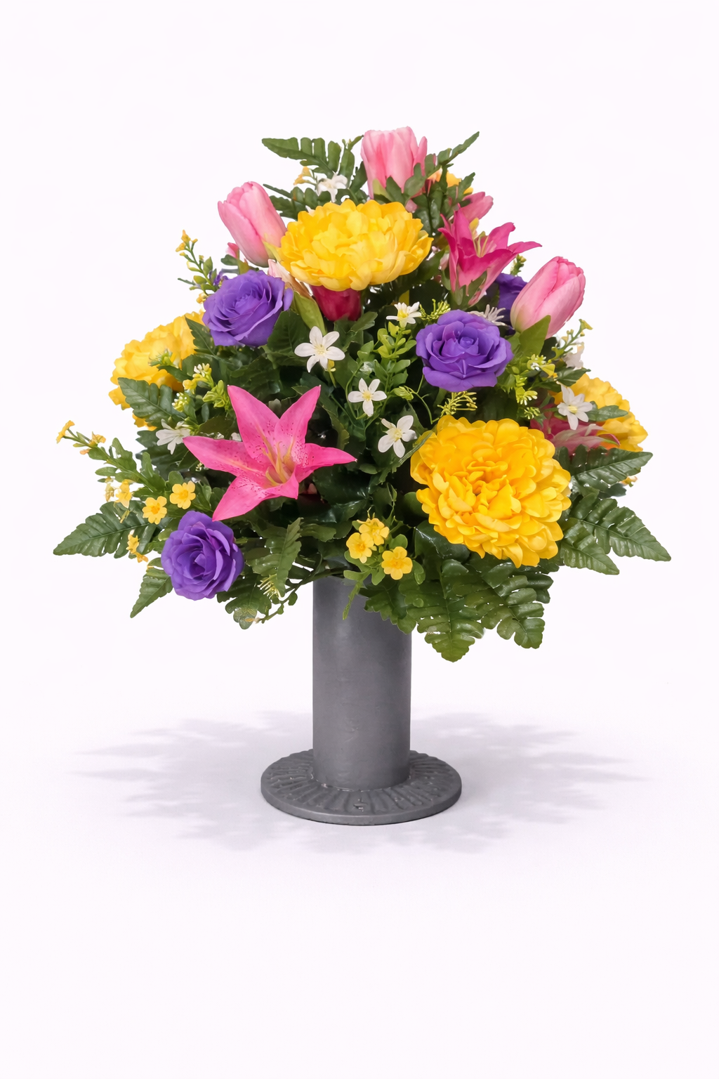Colorful mixed flower bouquet in a tall gray vase, featuring pink tulips, purple roses, yellow dahlias, white daisies, and pink lilies, on a white background.
