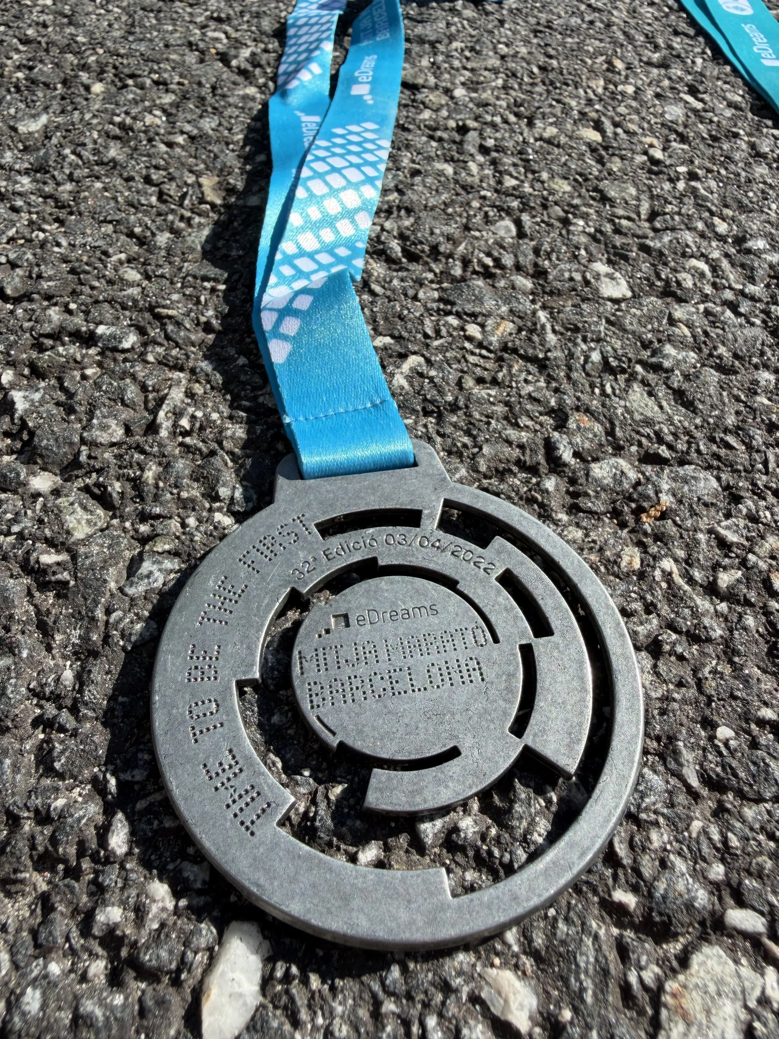 En metallplakett med inskripsjoner og en blå medaljebånd på en grusvei.
