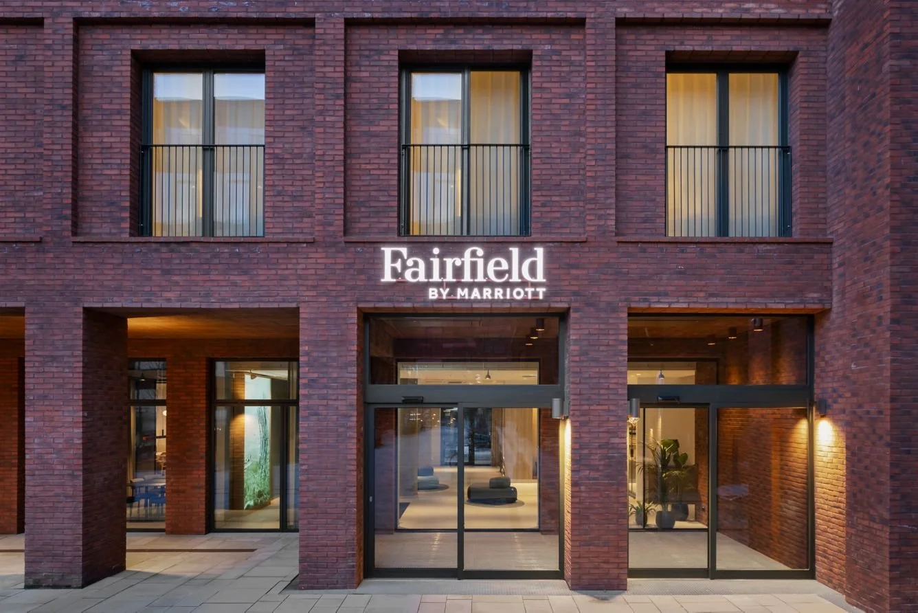 Hotellets inngangsområde i teglstein med innvendige lys og vinduer.
