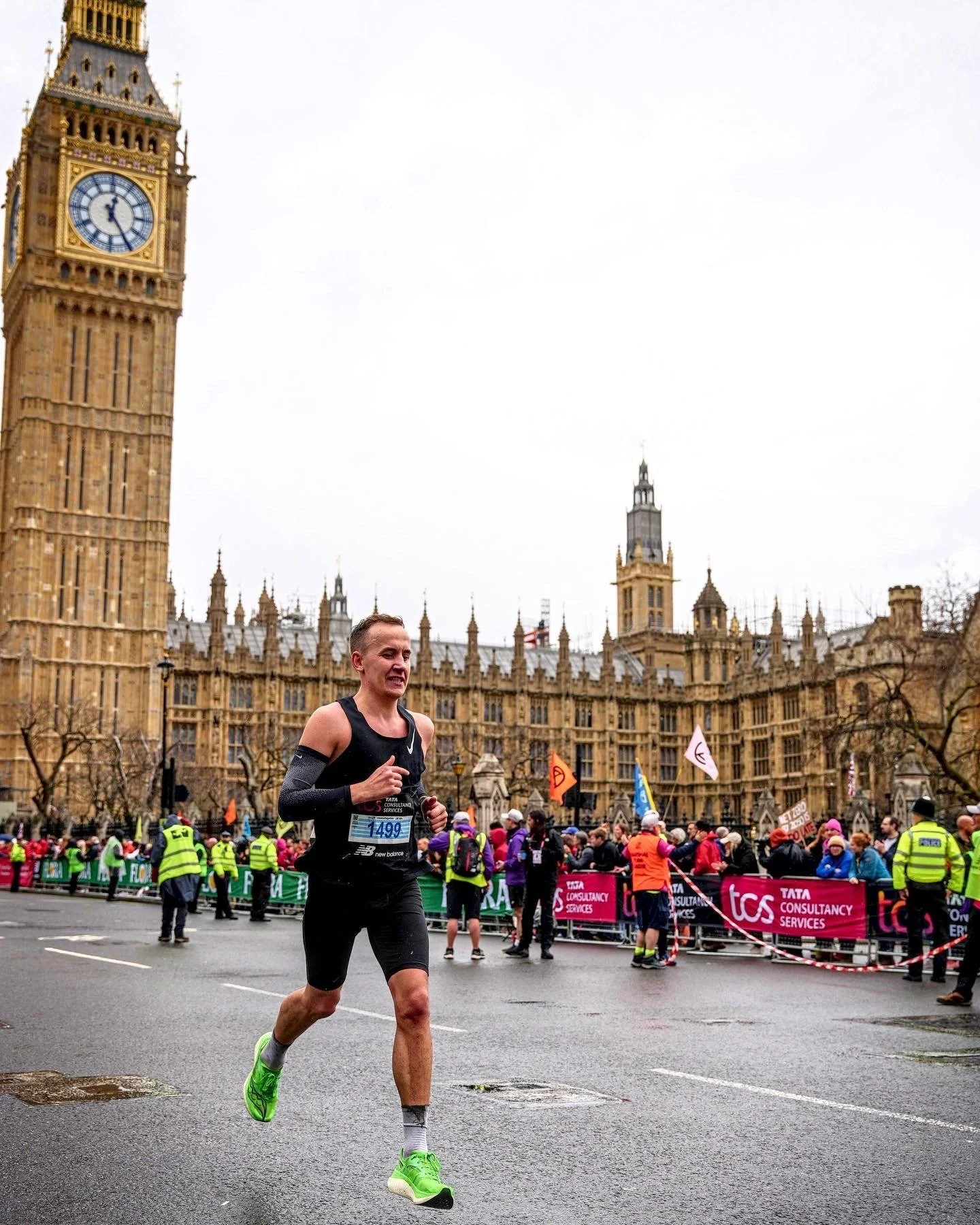 En mann løper i en maraton i London med Big Ben i bakgrunnen, omringet av tilskuere og sikkerhetsfolk.