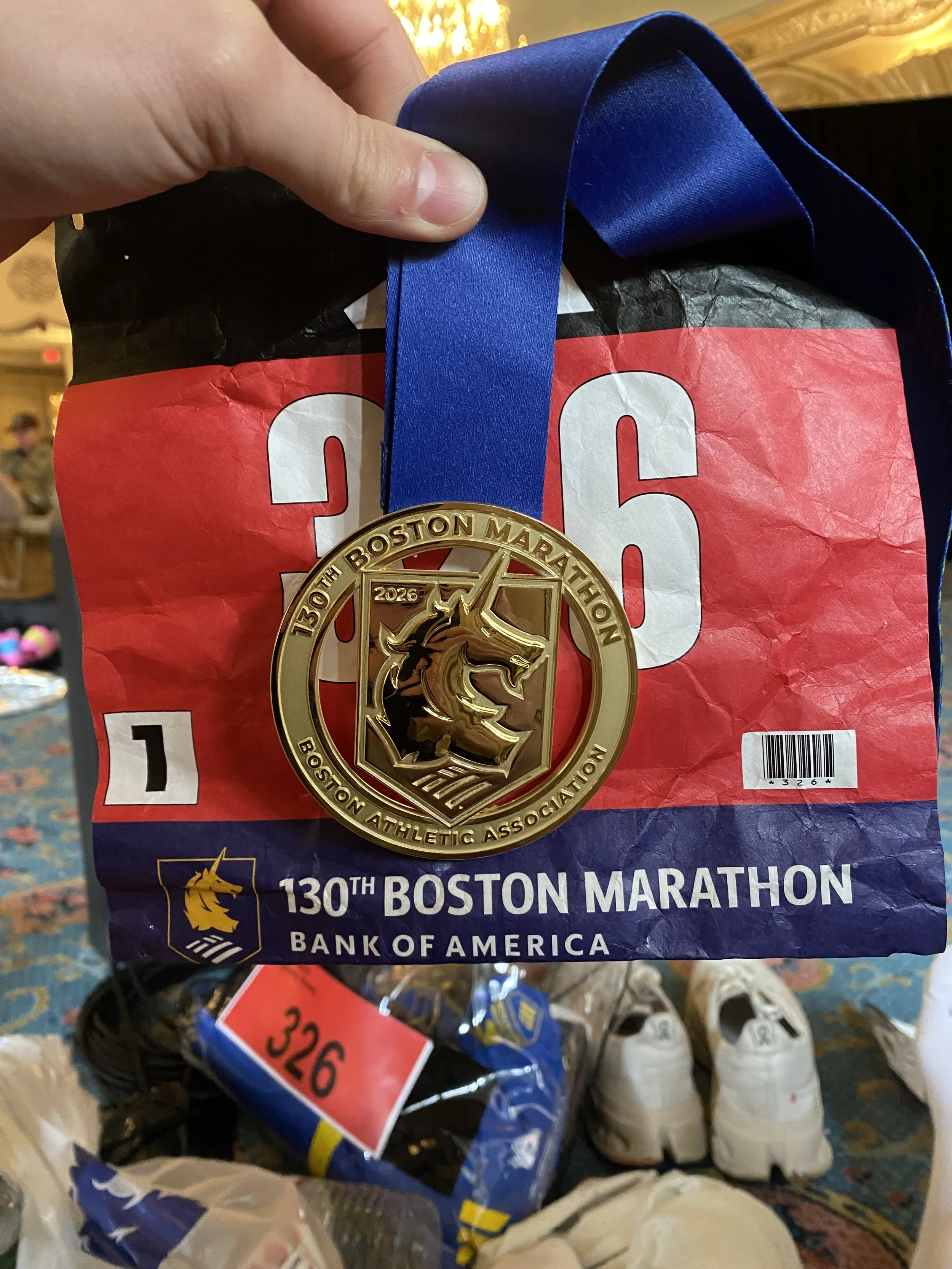 En løper med et medalje fra 130. Boston Marathon, en pose supermarkedspose fra Bank of America, og andre varer som sko og pakker med noe annet.