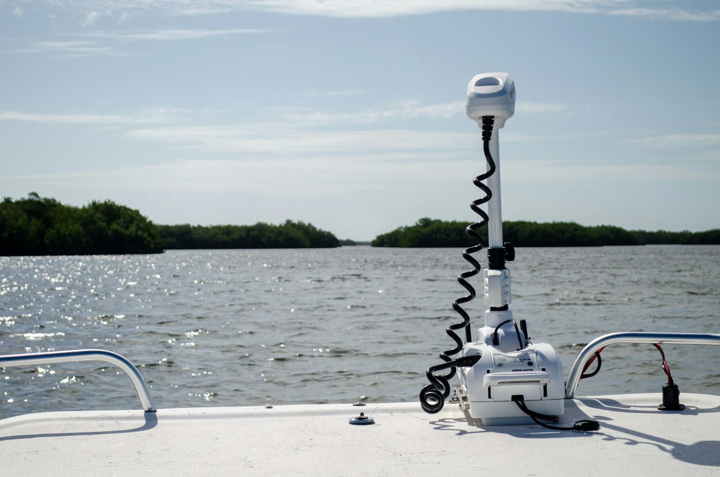 A fish finder attached to a boat on a body of water with green islands in the distance and a cloudy sky.