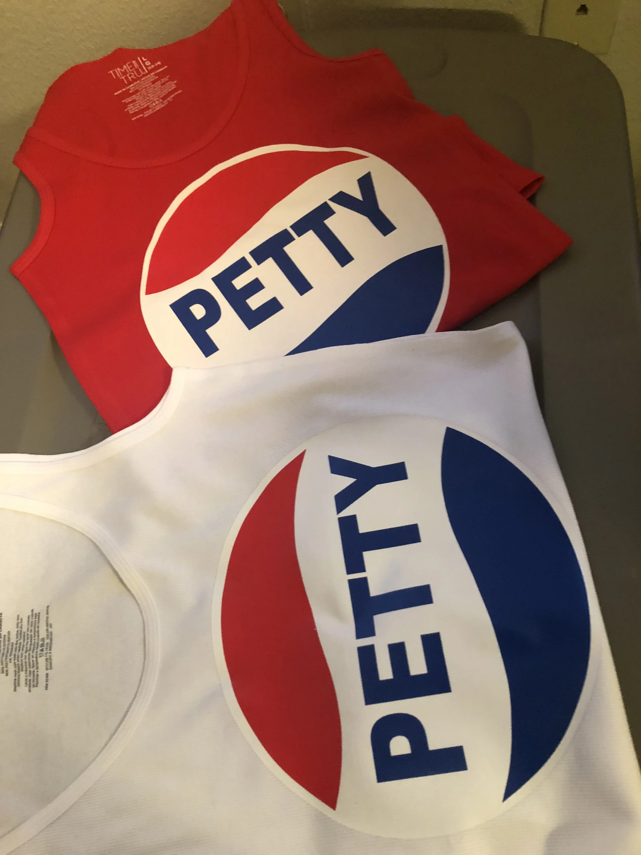 Two sleeveless tank tops, one red and one white, with the Pepsi logo and the word PETTY printed on the front.