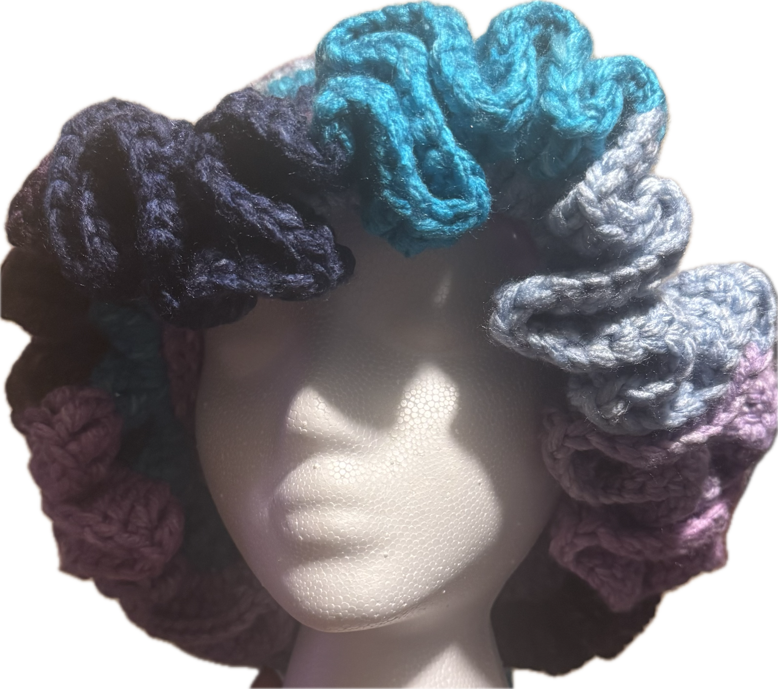 A mannequin head wearing a colorful, multi-colored crochet wig with large, thick yarn twists in shades of blue, purple, pink, gray, and black.