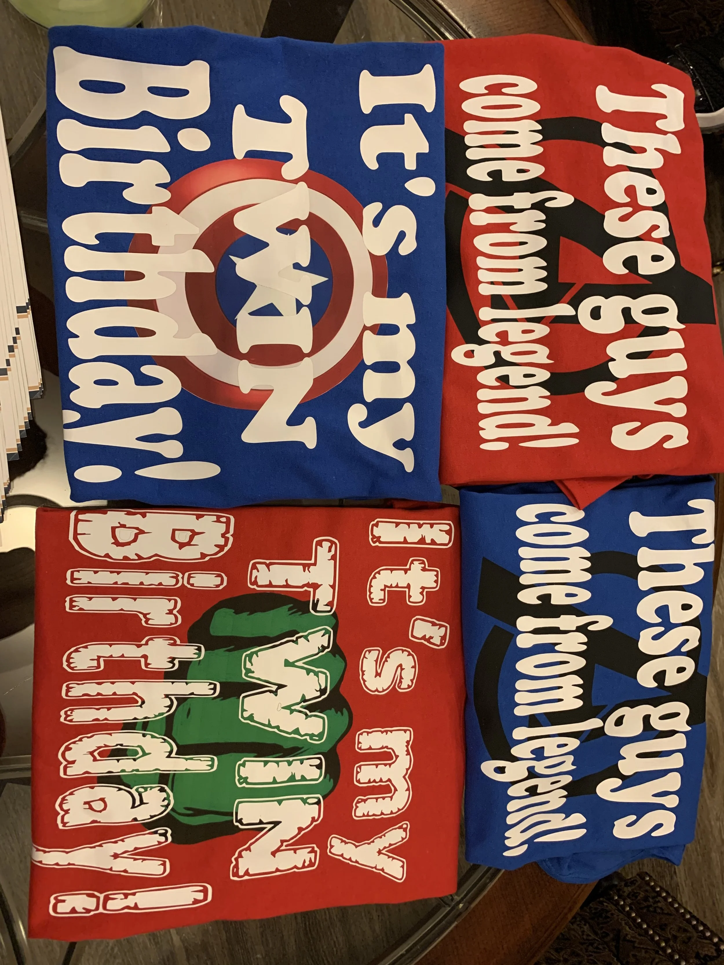 Four folded T-shirts with political and entertainment slogans: one red shirt with green and white M&M characters and 'I 