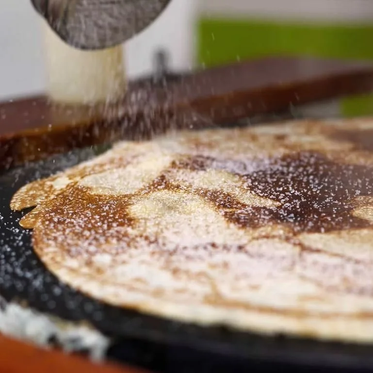 Dusting sugar on a freshly-made crepe