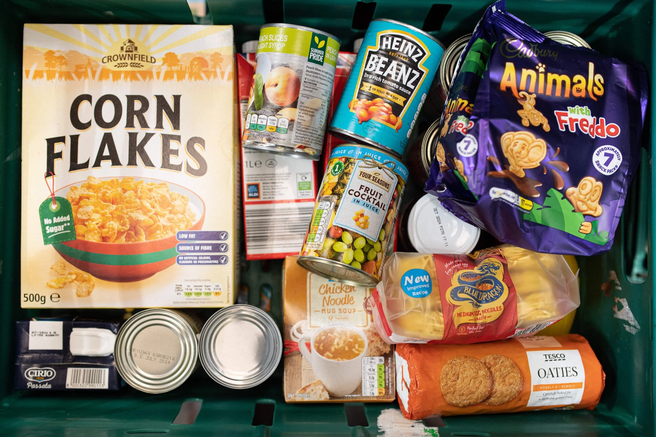 An image of a green crate containing donated food. The text to the left highlights the commitment from Locksmithery to Guildford Food Bank by donating 5% of net profits and conducting charity events