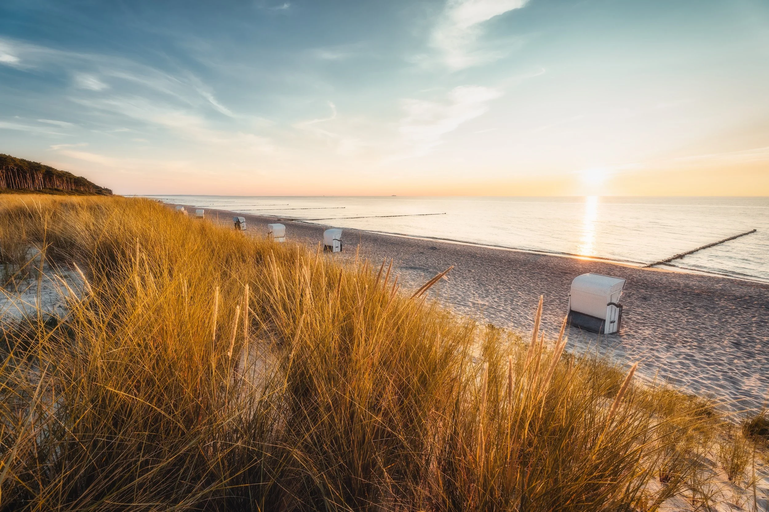 Strand bei Sonnenuntergang mit Dünen und Strandkörben