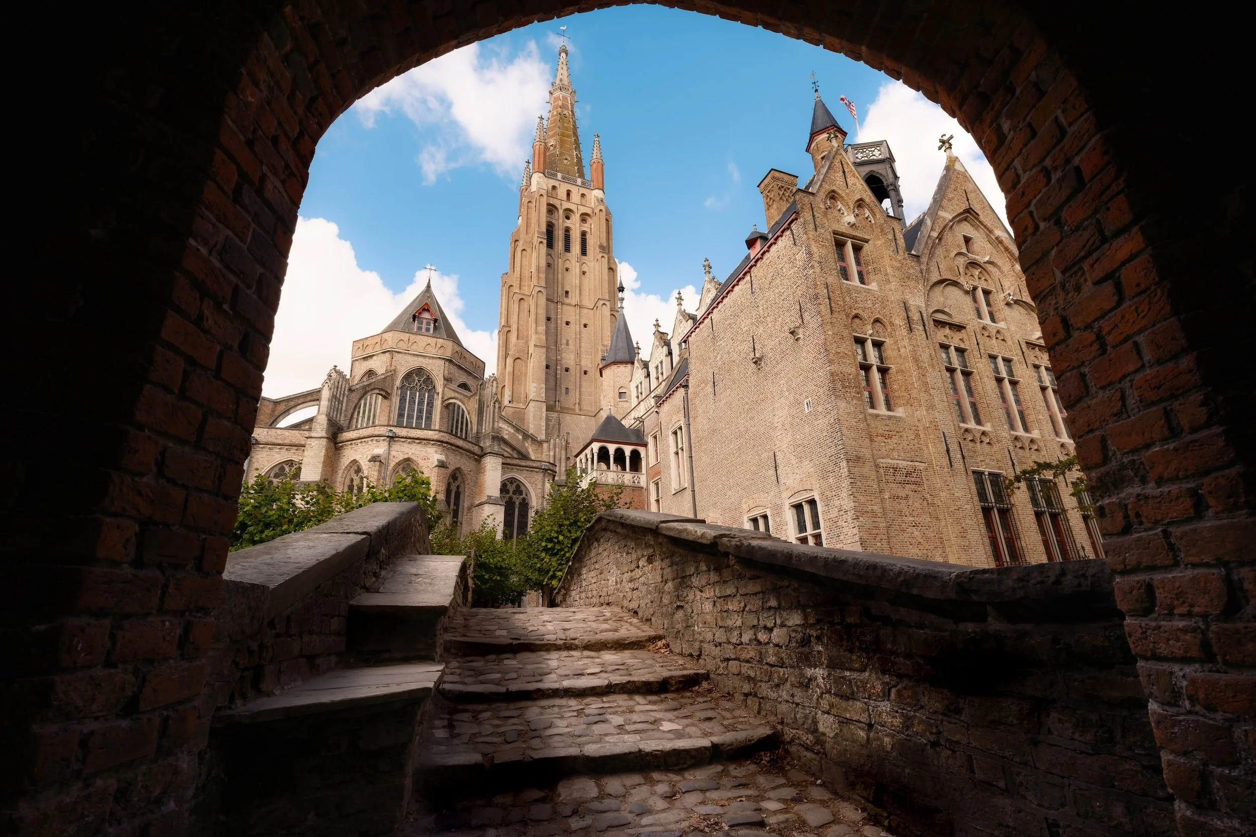 Blick auf das Château de la Cité aus einem Tor, mit steinigen Treppen und mittelalterlicher Architektur, während der Himmel blaut und Wolken zeigt.