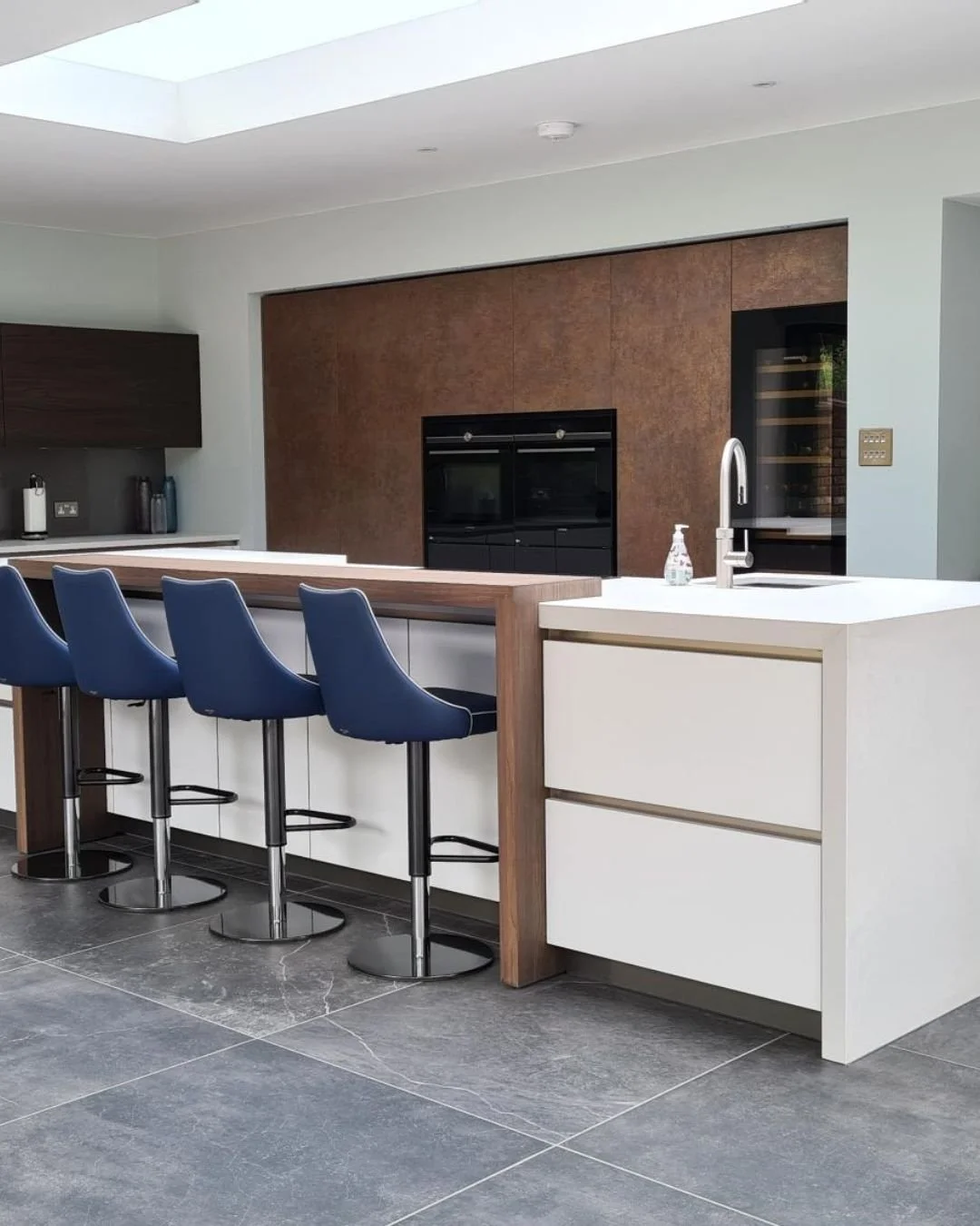 The island is where a kitchen either holds together or doesn't.

Here, navy cabinetry meets a white quartz worktop with a waterfall edge &mdash; the contrast deliberate, the proportion considered. Our team builds each island as a standalone piece of 