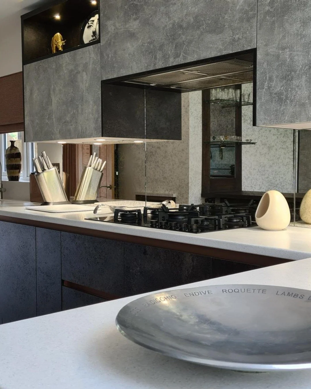 This dramatic kitchen oozes "hotel luxury". Dark cabinetry, a mirrored splashback and a marble worktop that reflects every hour of the day differently.

This project was designed for a client who wanted drama without clutter. Our team speci