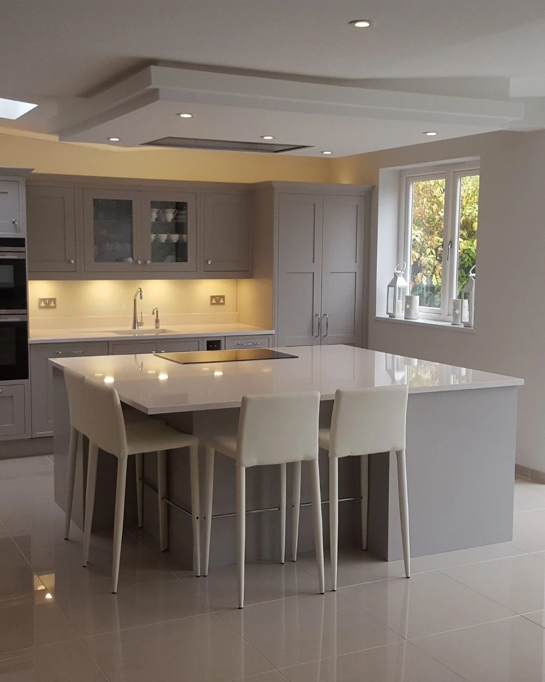 A light grey kitchen, large island and a worktop that extends the full width of the room.

What makes this work is the proportion - the island is exactly wide enough, the overhang exactly right for seating, the gap between island and run exactly enou