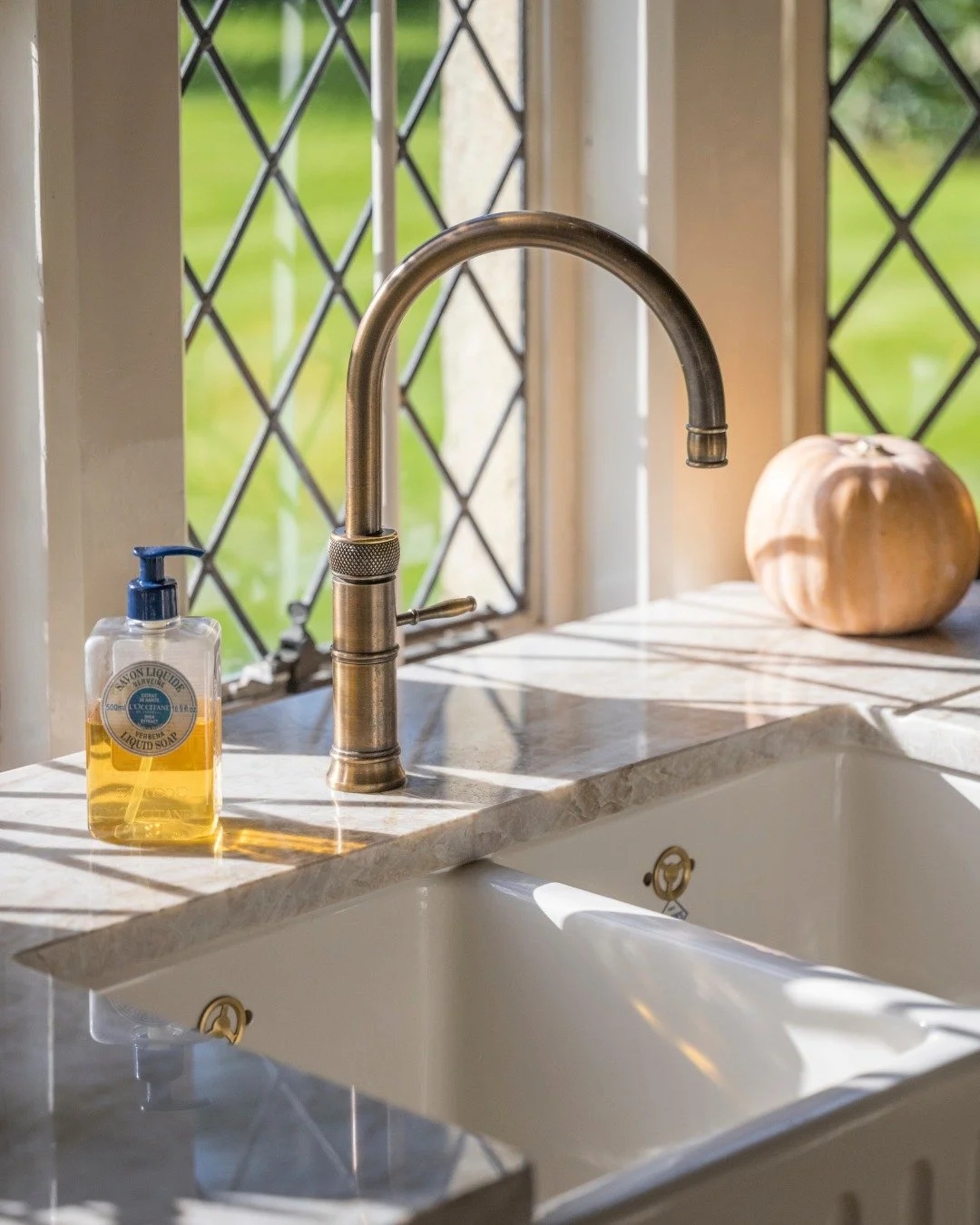 Patinated Brass tap by @quookeruk, a butler sink and leaded windows catching the morning light.

This tap was chosen for the way it sits - the height of the arc, the weight of the lever, the warmth of the finish against the cool of the marble worktop