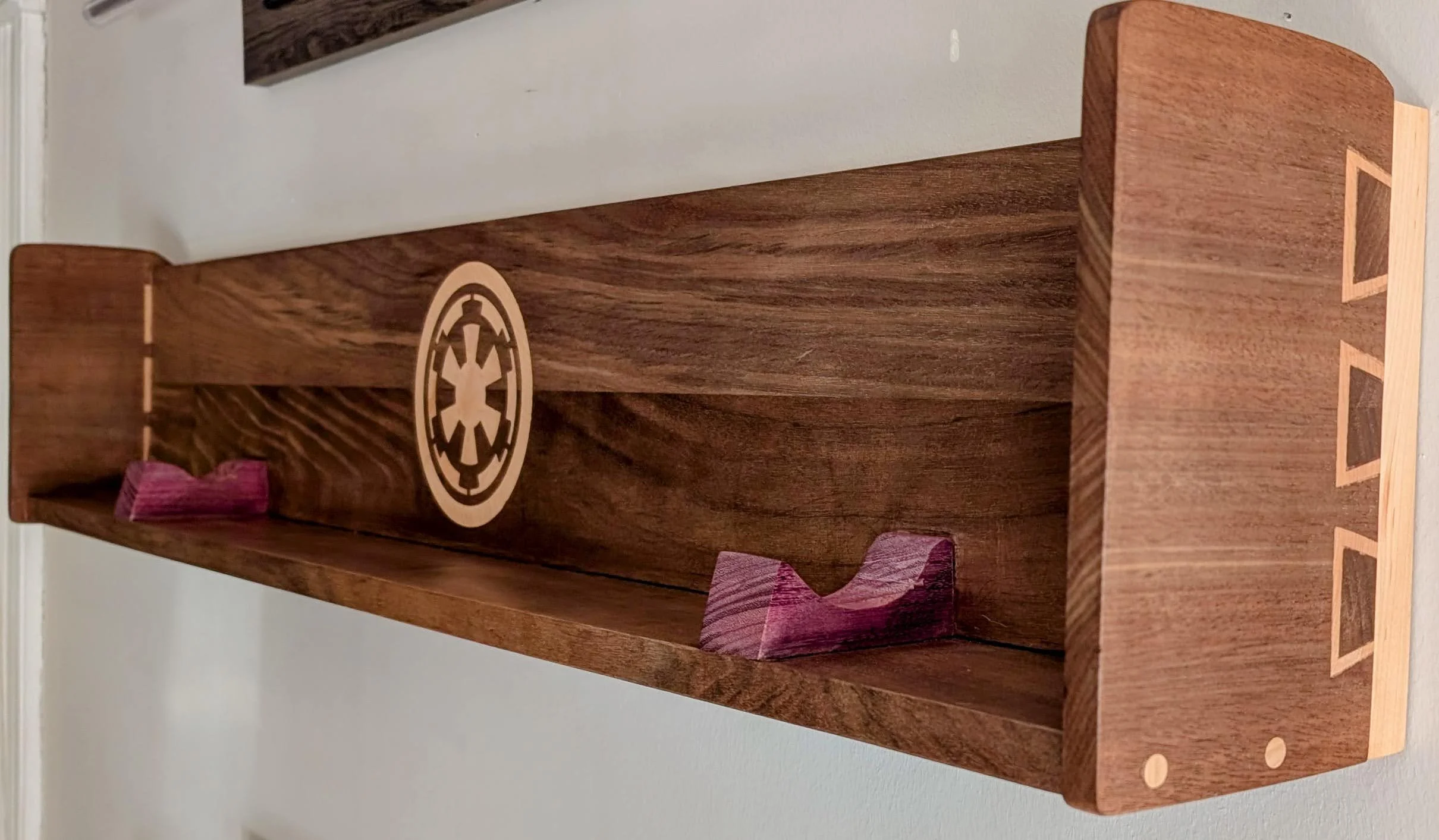 Wooden shelf with Star Wars emblem and purple-painted support blocks.