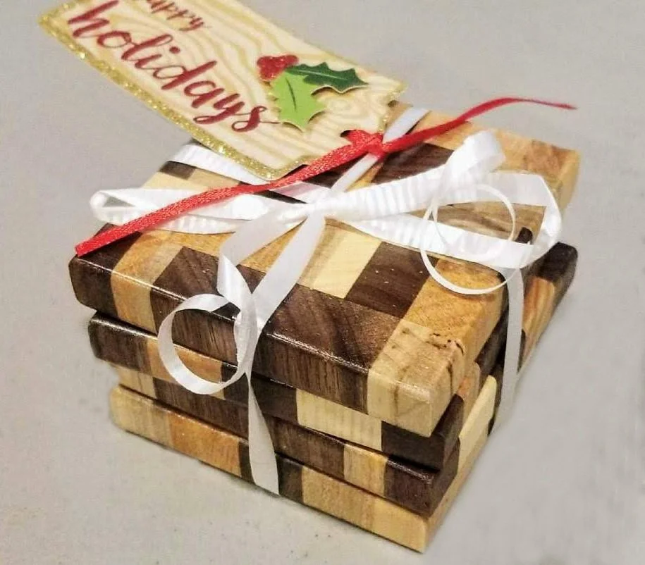 A small wooden Christmas gift box with a ribbon, holly leaves, and a holiday tag.