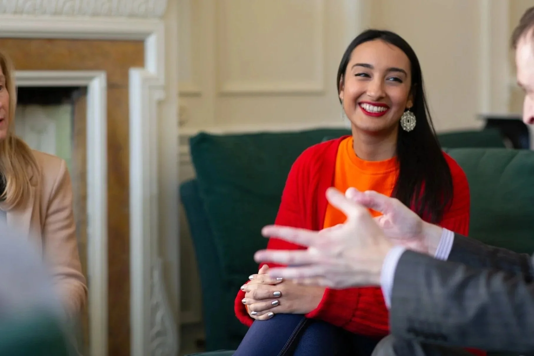 Chandni Rajput, BACP-registered counsellor and therapist smiling at a formal meeting in a counselling room engaging in conversation with another person whose hand is visible gesturing.