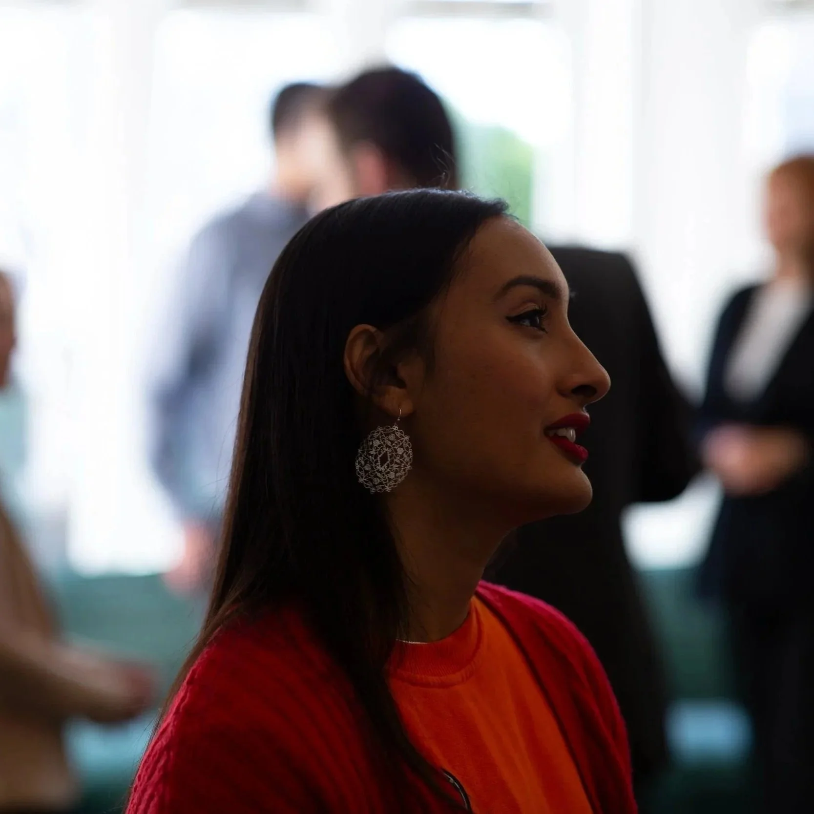 Chandni Rajput, counsellor and therapist, standing in front of a window with other people blurred in the background.