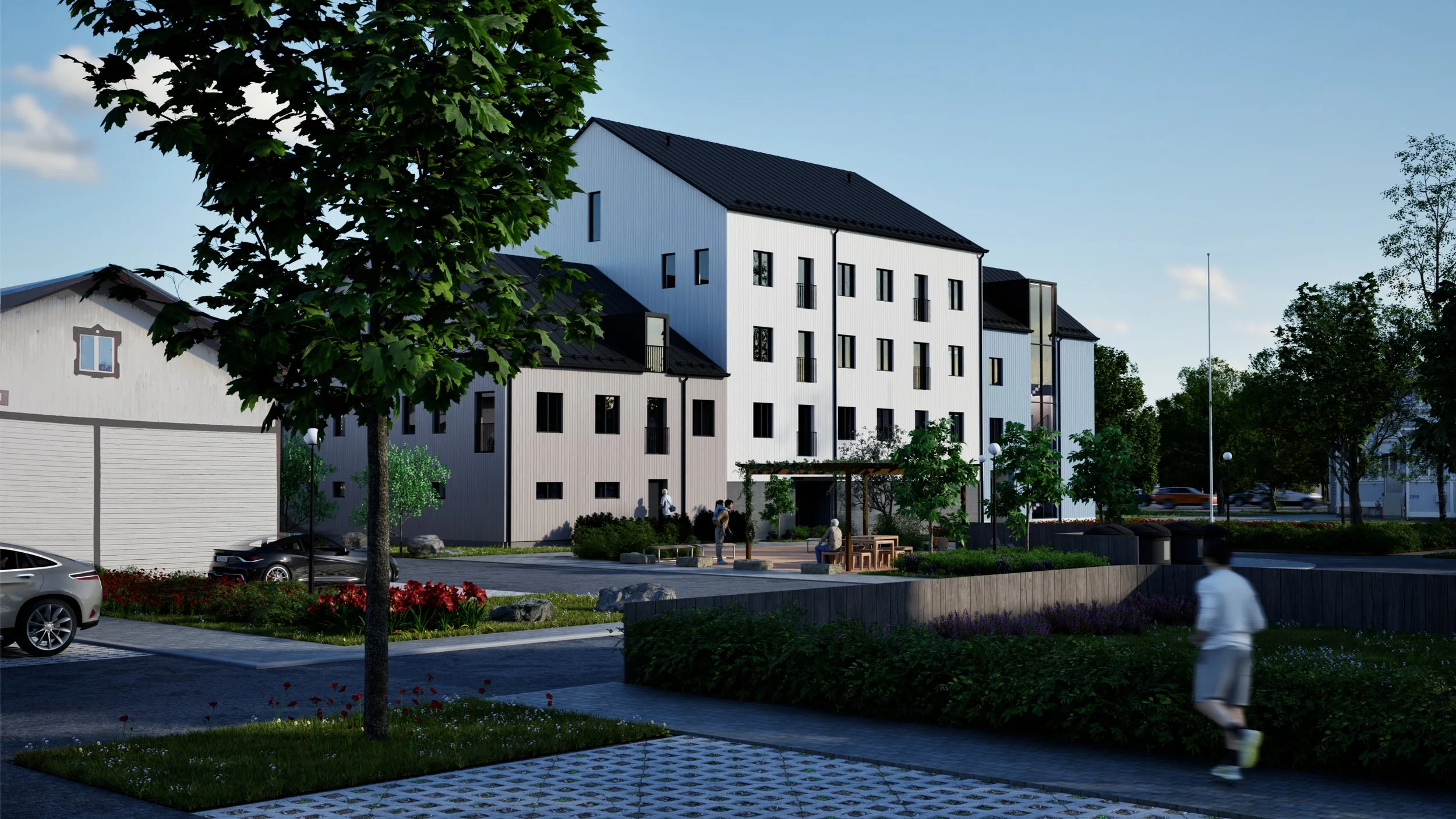 Kuvassa on moderni, harjakattoinen kerrostalo, puita, ihmisiä istumassa ja kävelemässä, parkkialue ja pensaita, kukkapenkkejä ja ulkoterassi.