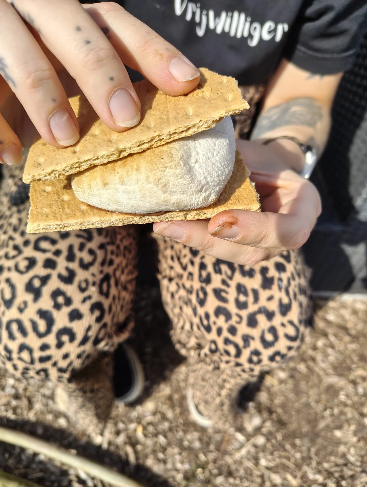 Persoon houdt een ijsje met waffle wafel en vanille ijs in handen, gekleed in leopard print broek.