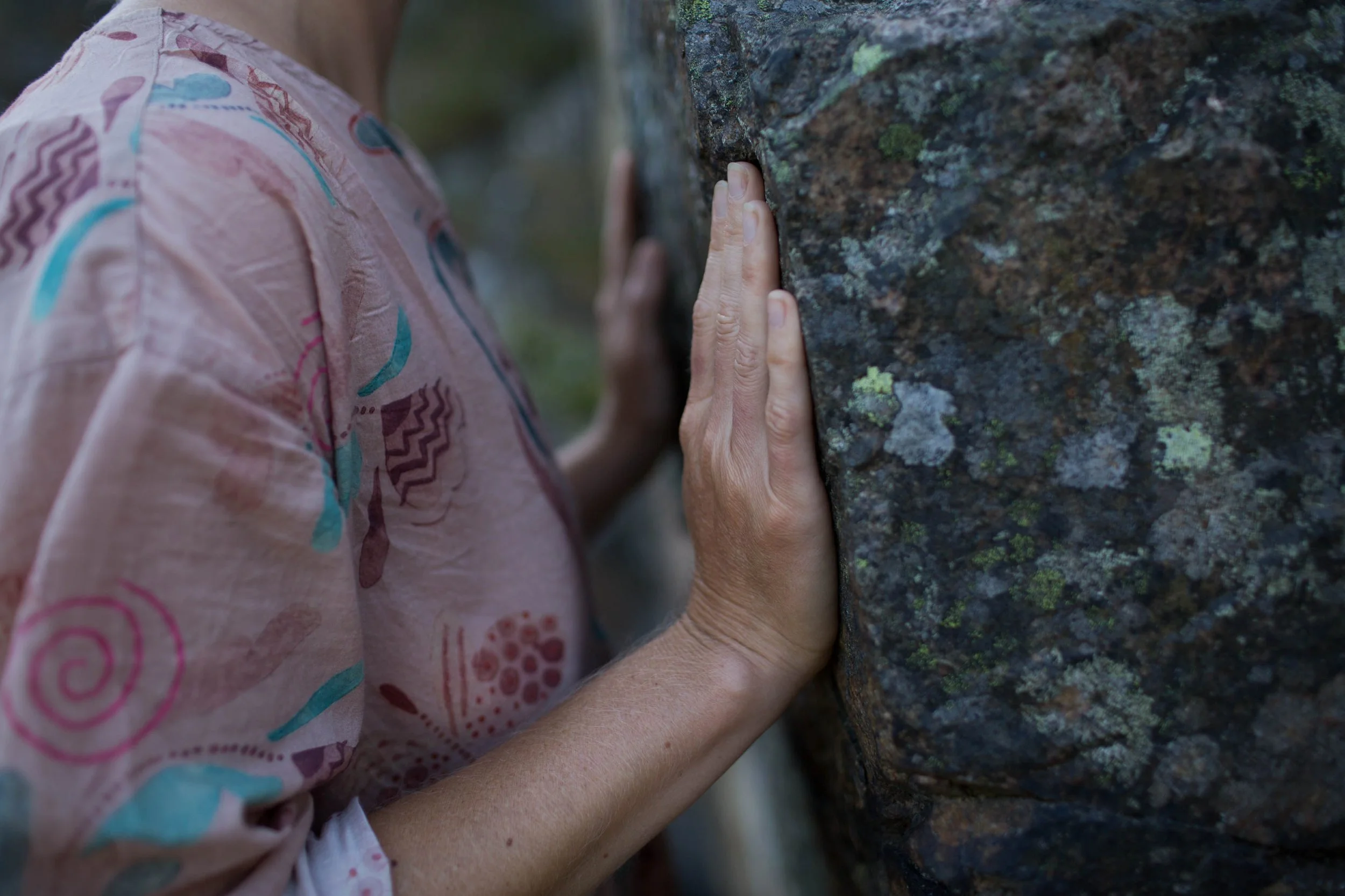a close-up of a woman's chest and hands touching a vertical rock
