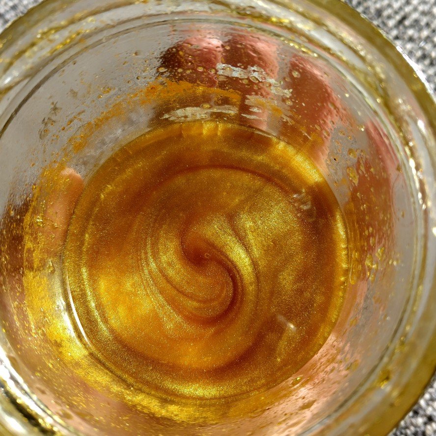 Close-up view of a root beer float with a swirl pattern in the glass, showing golden-brown color and bubbles.