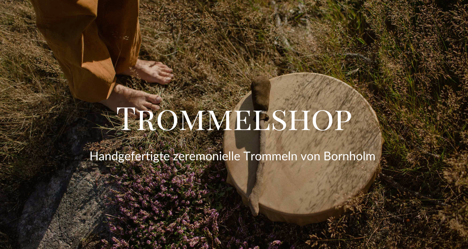 Handgefertigte Timpeltrommel auf der Erde, umgeben von Gras und Pflanzen, mit einer Person, die barfuß daneben steht.