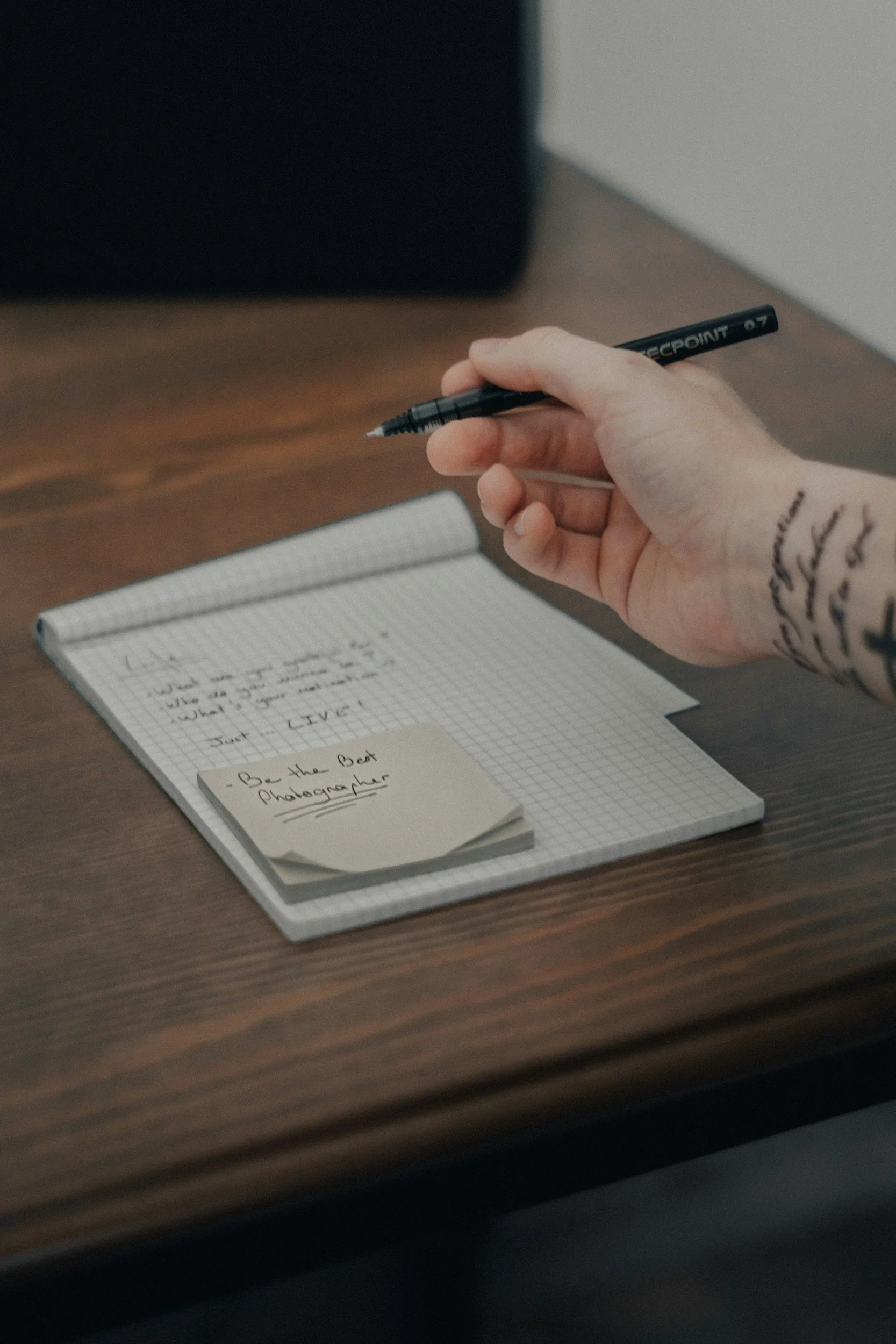 a hand holding a pen over a notepad
