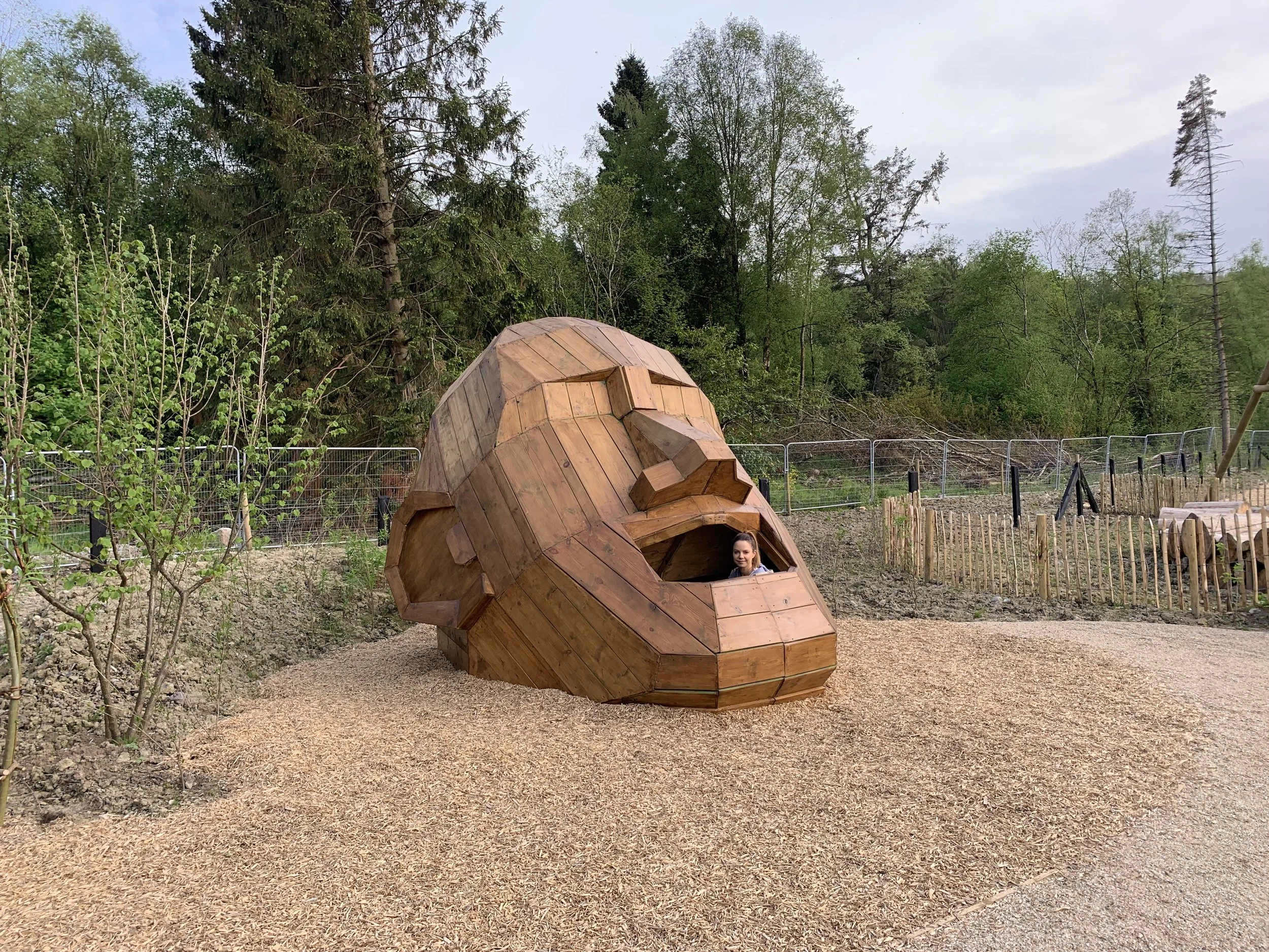 Wooden animal-shaped playhouse designed like a squirrel, with a girl looking out from an opening.