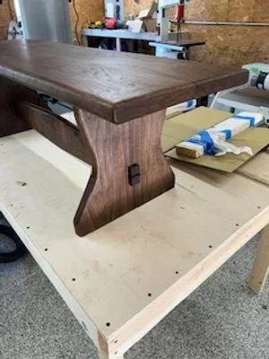 A wooden table top placed on a workbench in a workshop.