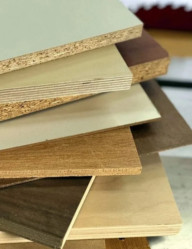 Stacked sheets of various types of wood and laminate materials in different colors and finishes.