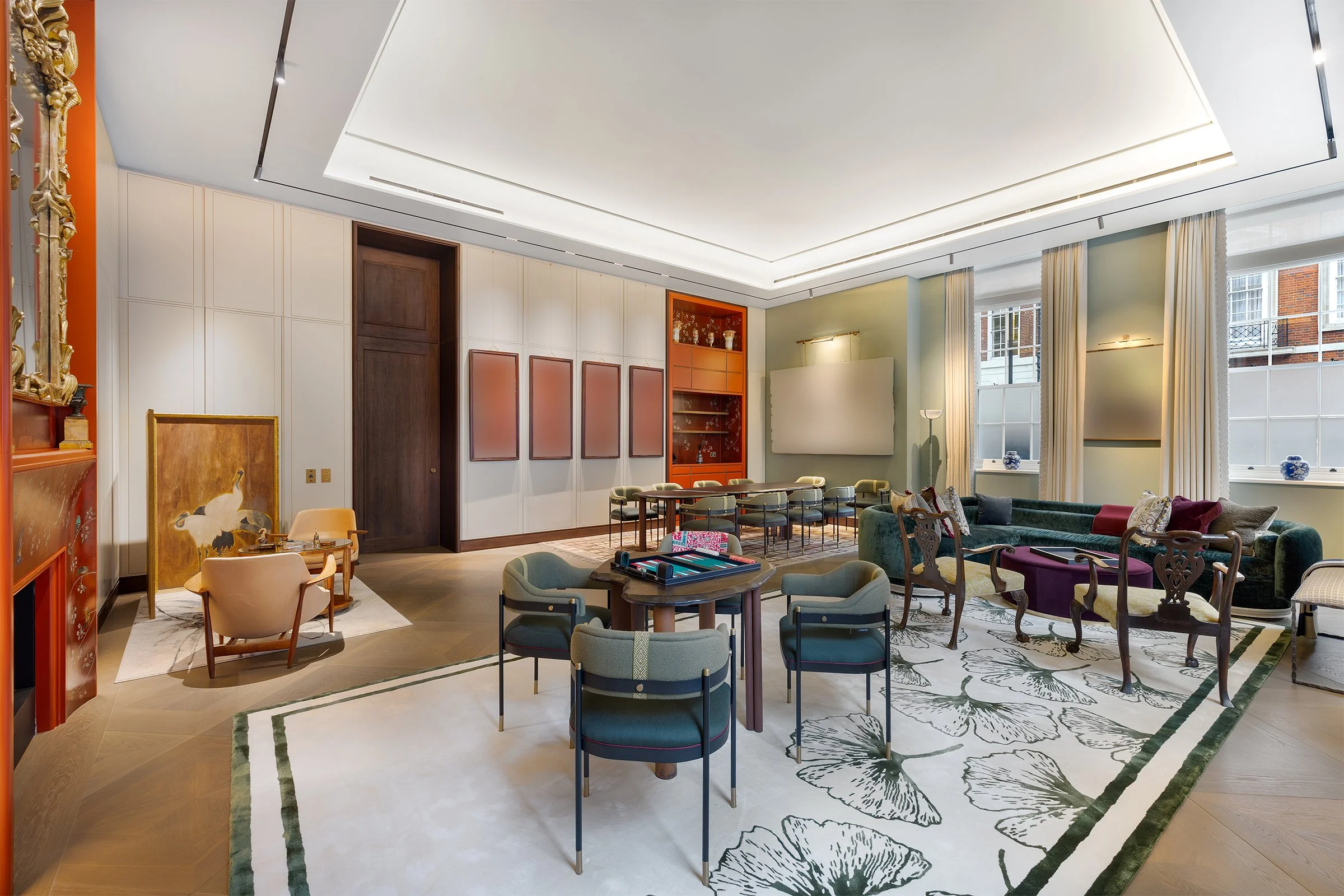 Elegant living or conference room with large windows, a variety of chairs and sofas, a white patterned rug, and decorative elements on the walls and shelves.