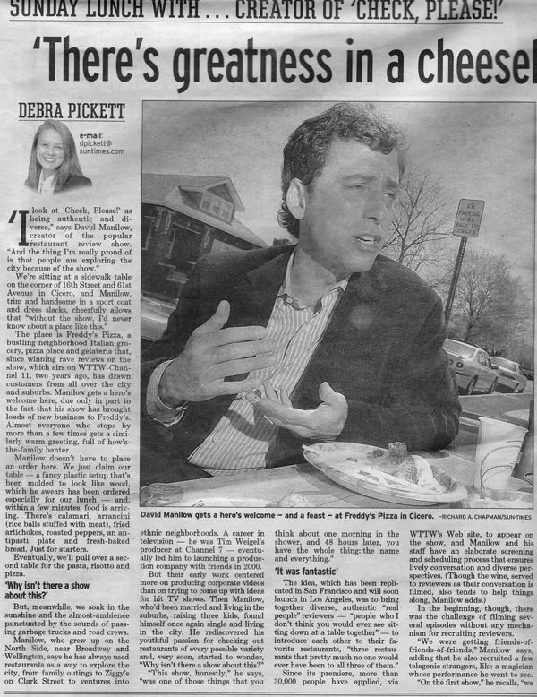 A black and white newspaper article featuring a man with dark curly hair in a suit, talking and gesturing with his hands during an event at Freddy's Pizza. The article title is "There's greatness in a cheese" and the author is Debra Pickett.