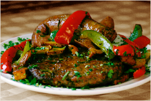 Beef stir-fry with red and green bell peppers and green onions on a white plate
