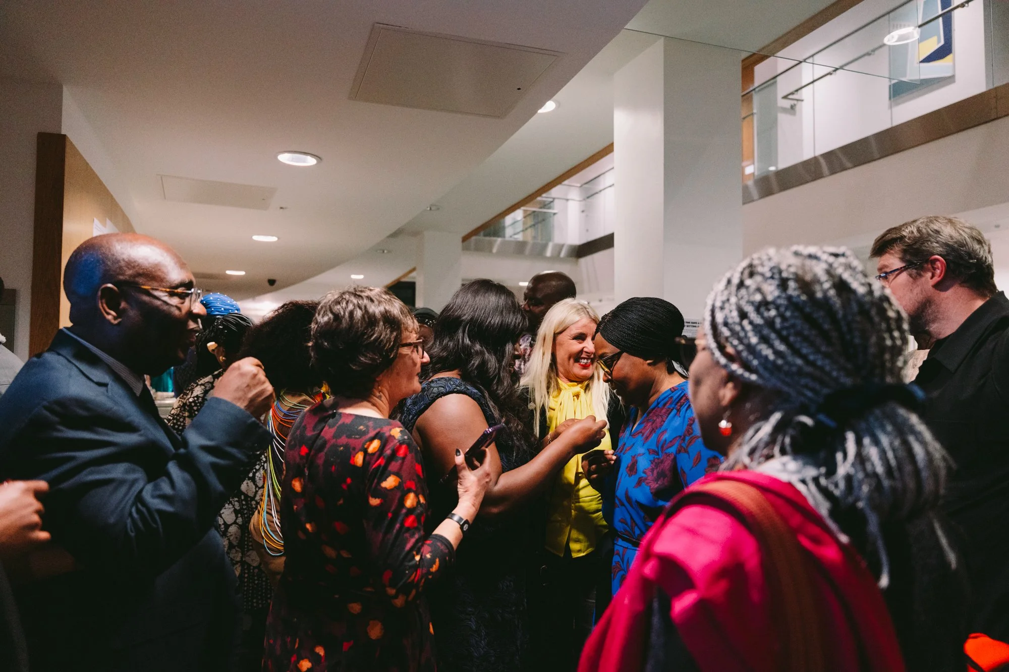 Group of diverse people socializing and smiling at an indoor event.