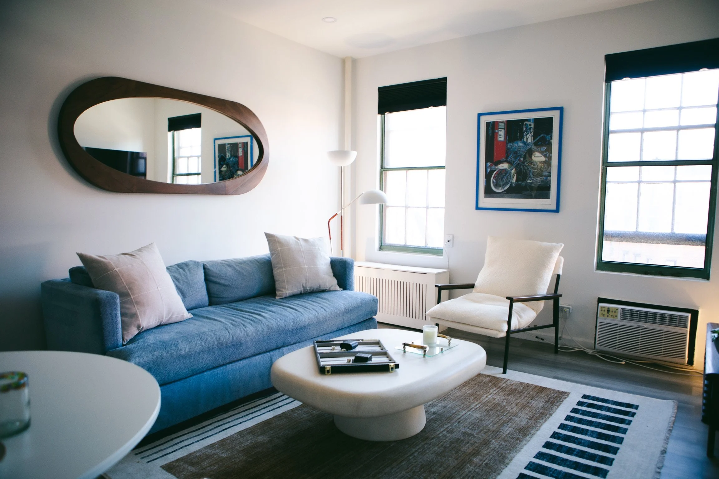 A blue couch positioned in a room with a large mirror reflecting the space.
