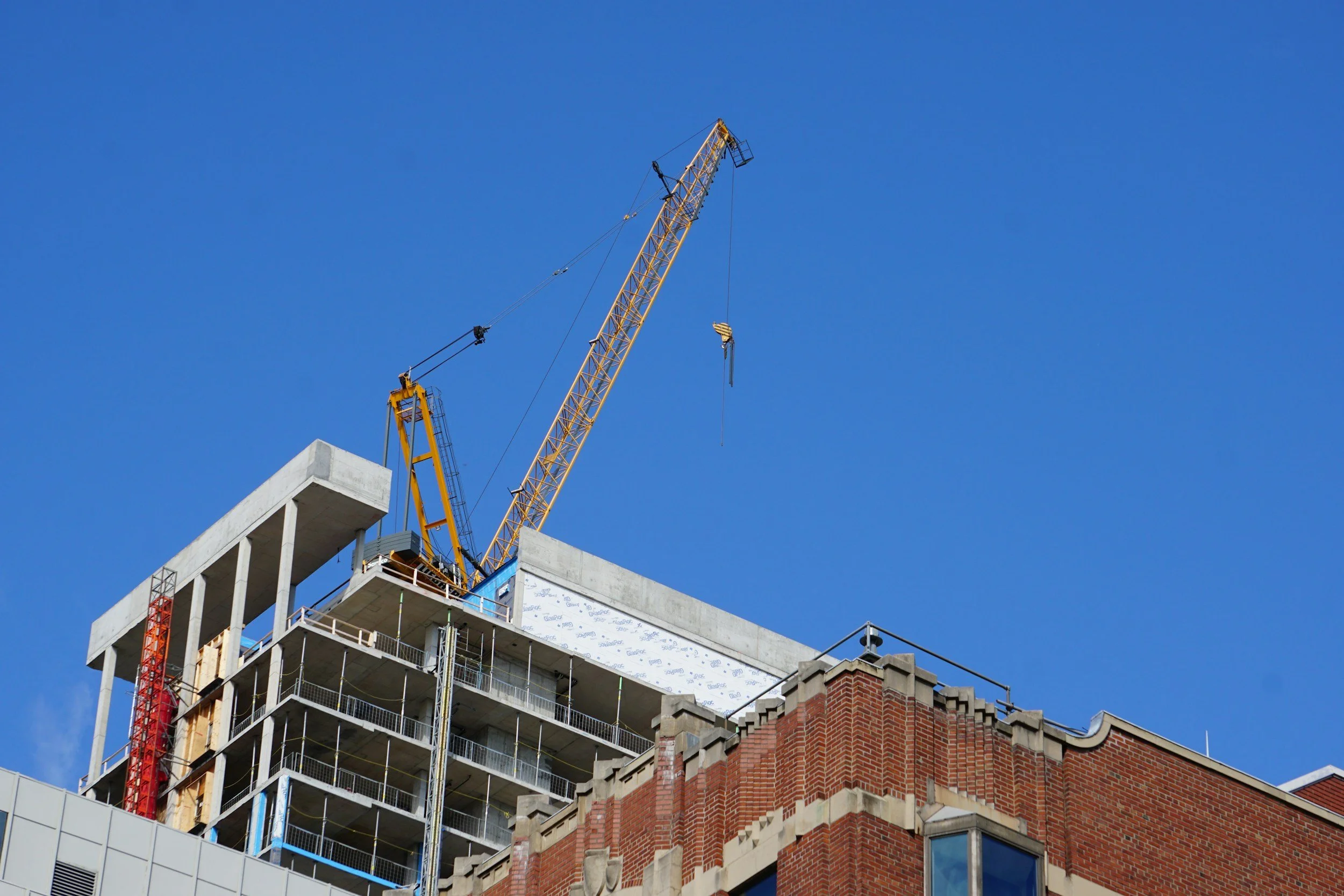 Baukran auf einem mehrstöckigen Gebäudebau unter blauem Himmel.