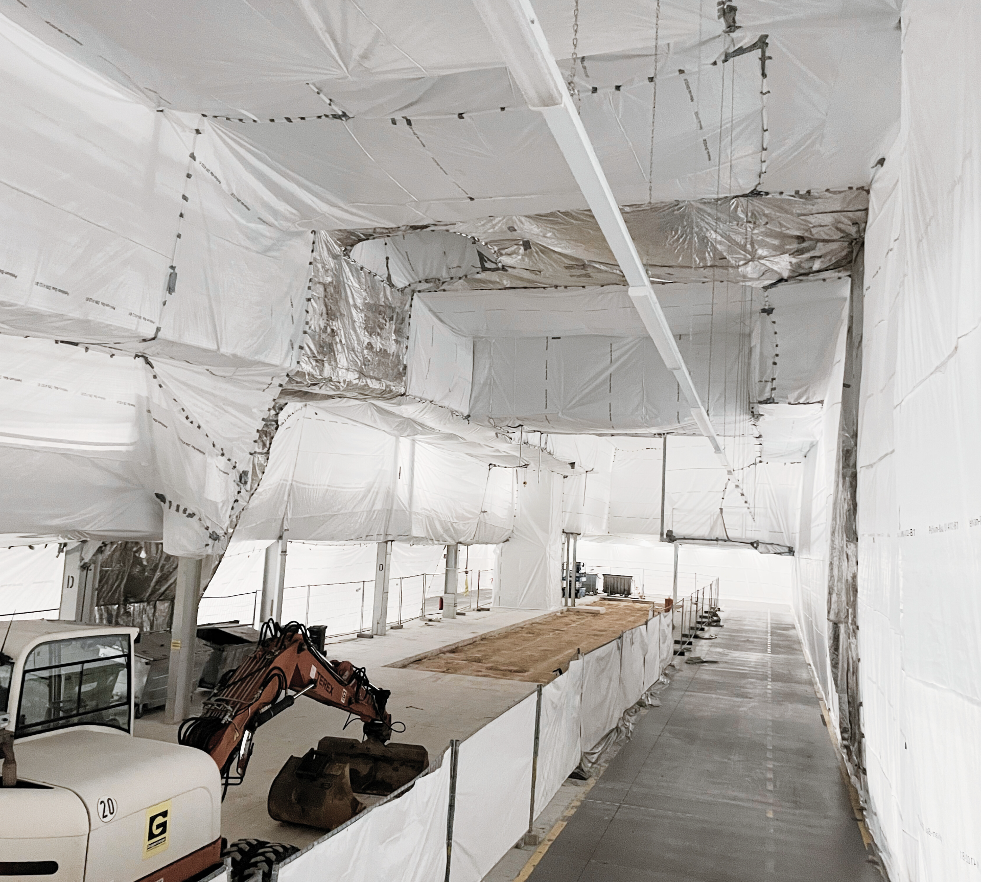 Innenansicht eines Gebäudes im Bau mit weißen Abdeckplanen, Gerüsten und Baumaschinen