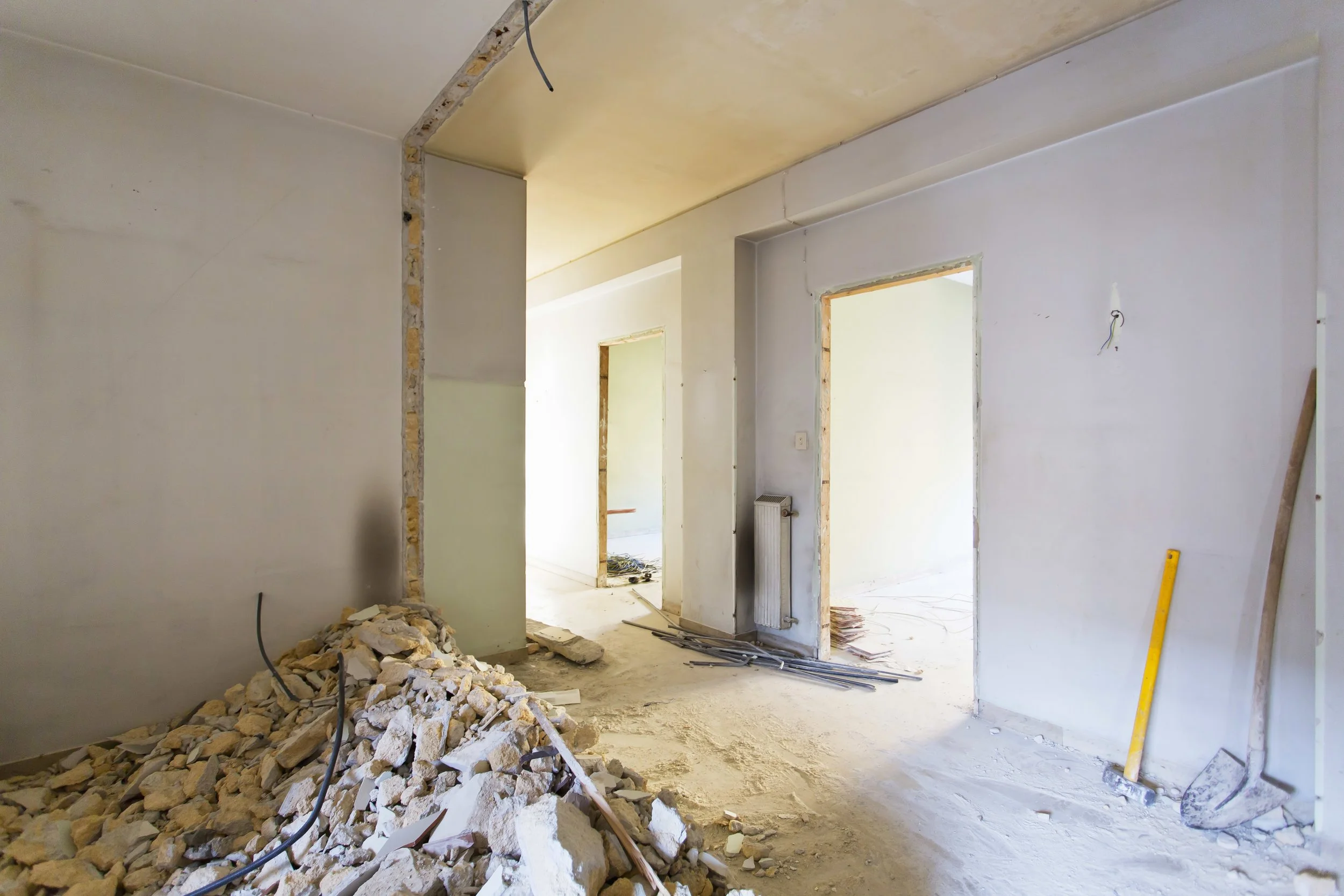 Interiores de una construcción en progreso, con paredes en proceso de acabado y escombros en el suelo.