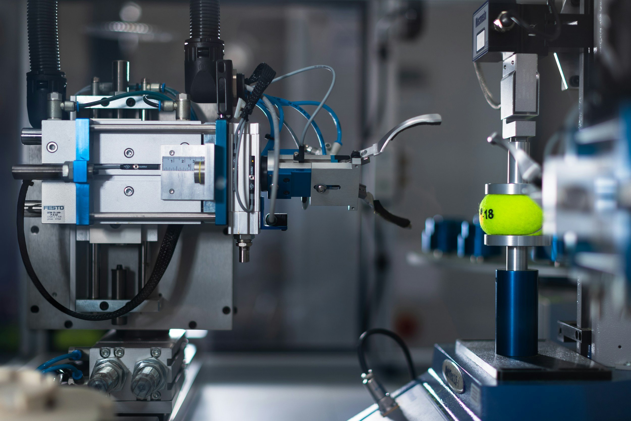 Close-up view of a complex piece of industrial machinery with various metal components, pneumatic tubes, and wires, used in manufacturing or scientific research.