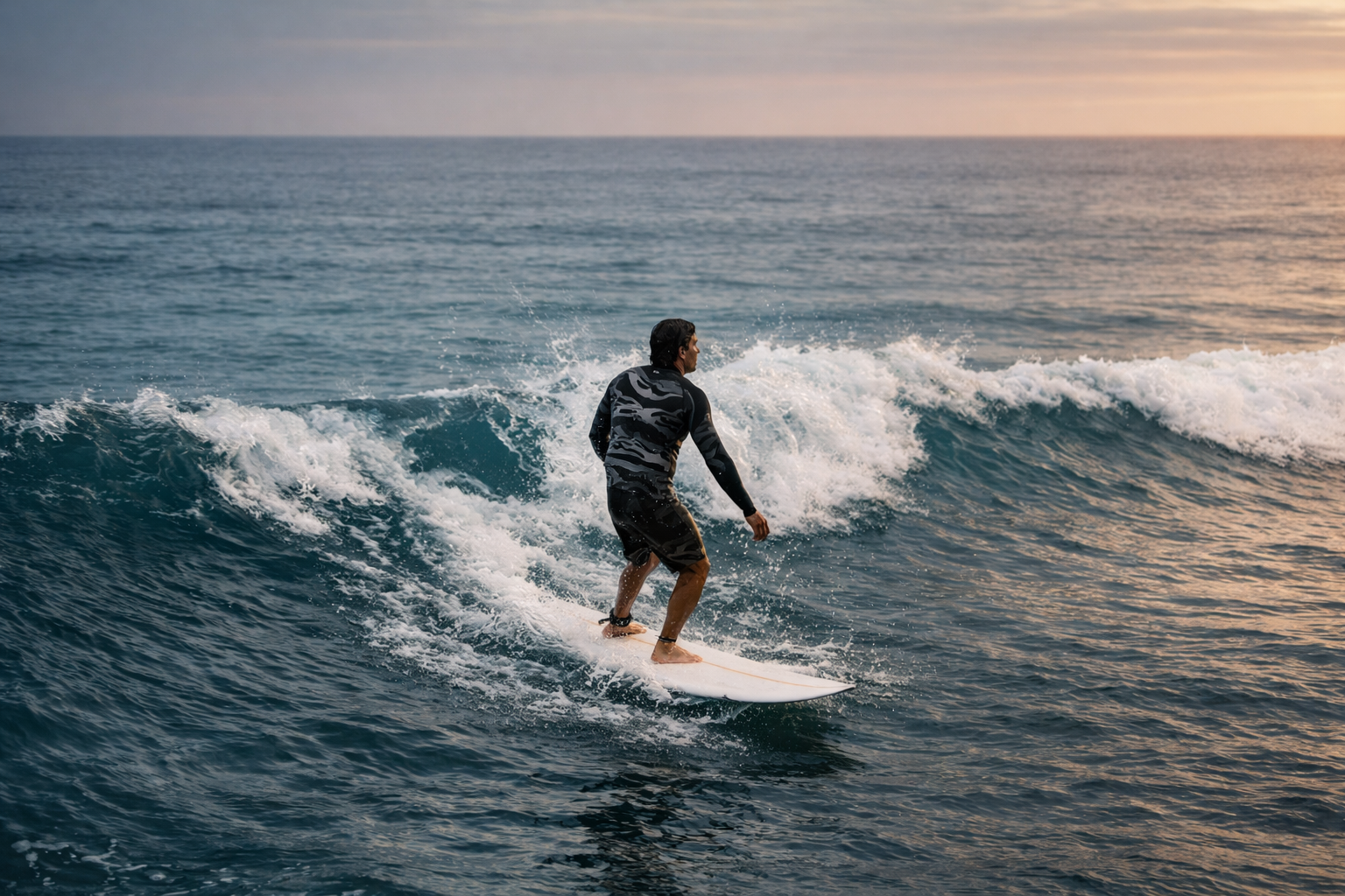 A man surfing on a wave during sunset in the ocean.
