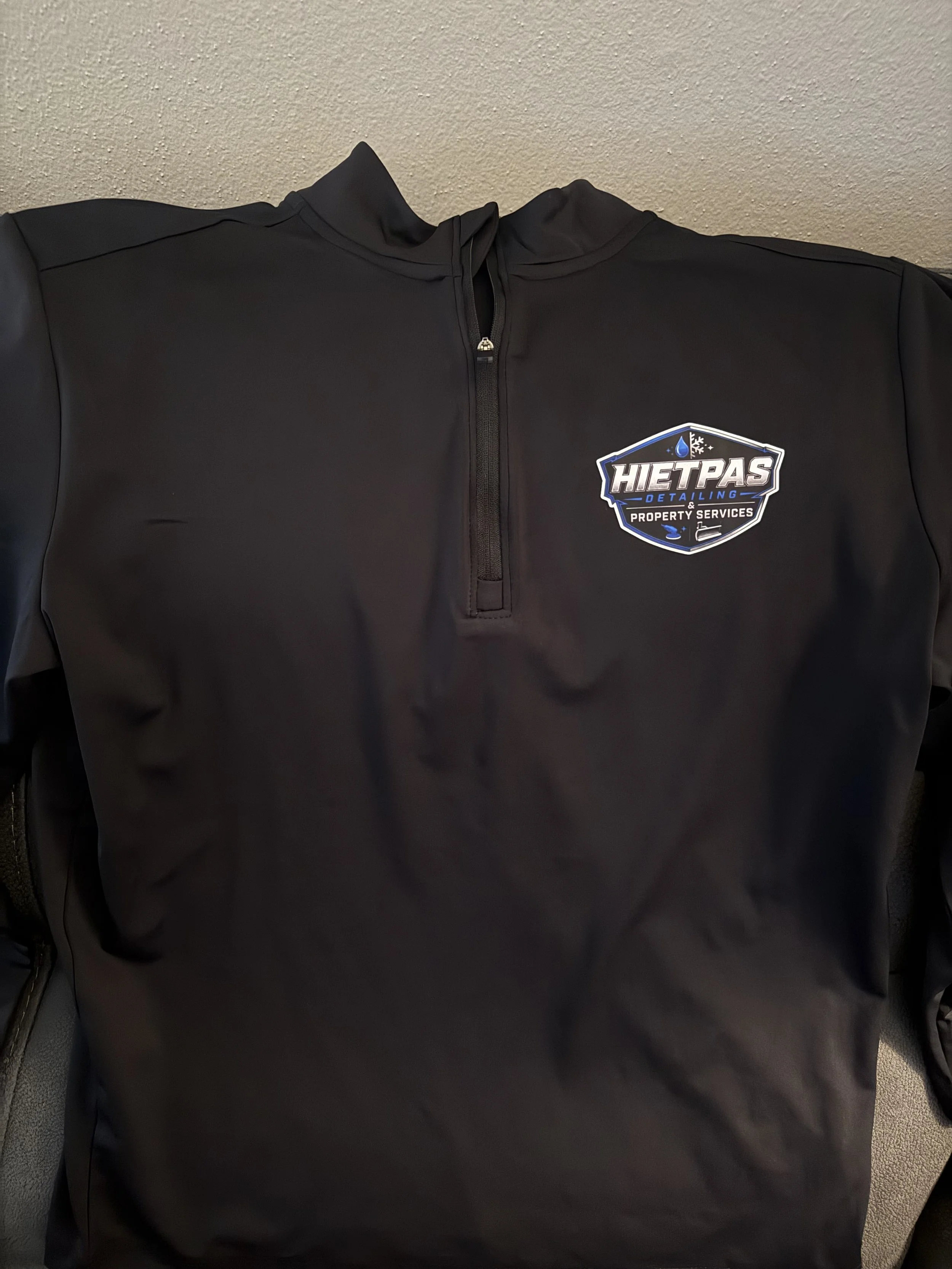 Custom DTF printed logo on a black performance quarter-zip pullover for Hietpas Detailing & Property Services.