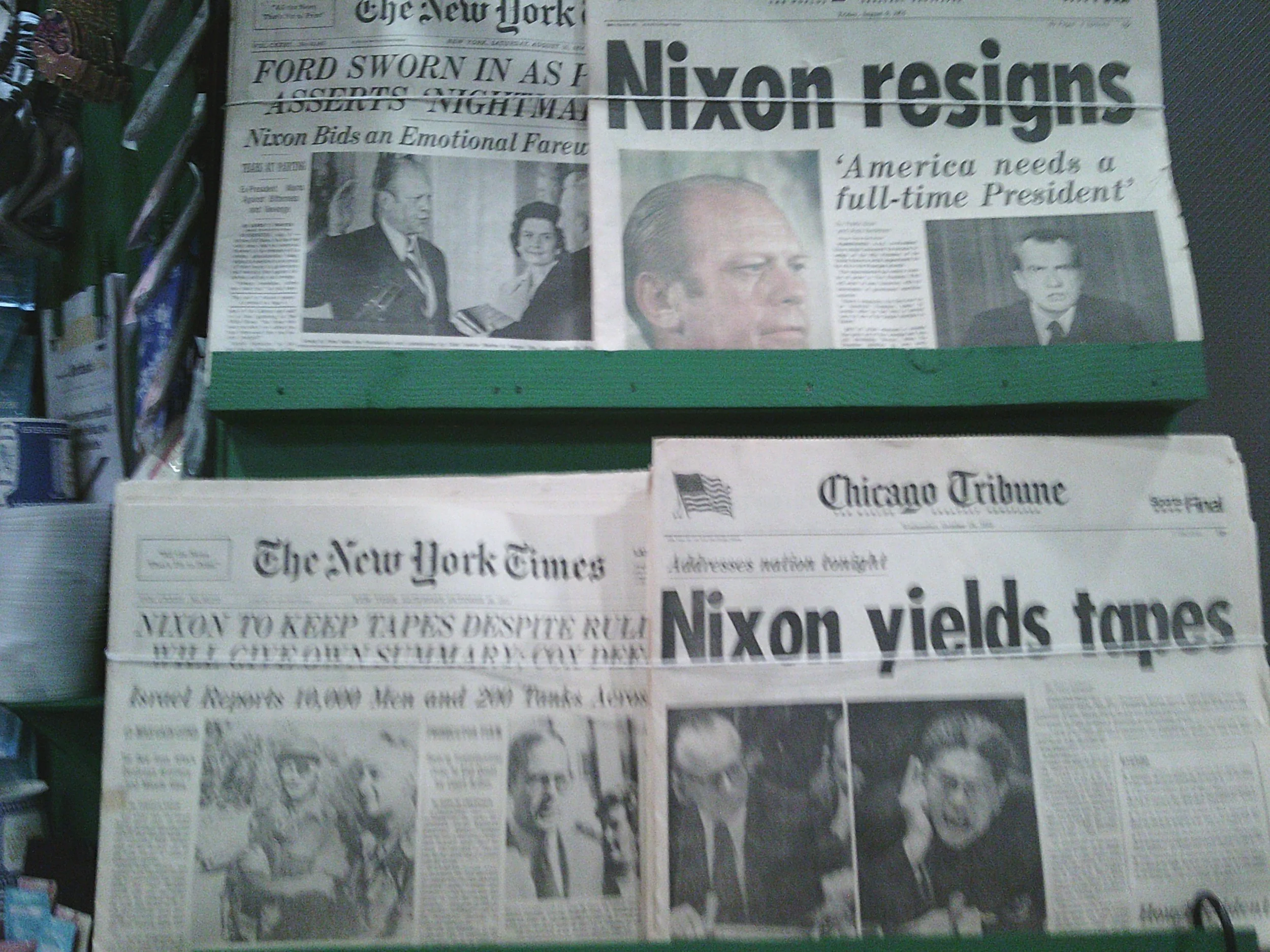 Several newspapers on display, featuring headlines about Nixon resigning and Nixon yielding tapes, including The New York Times and Chicago Tribune.