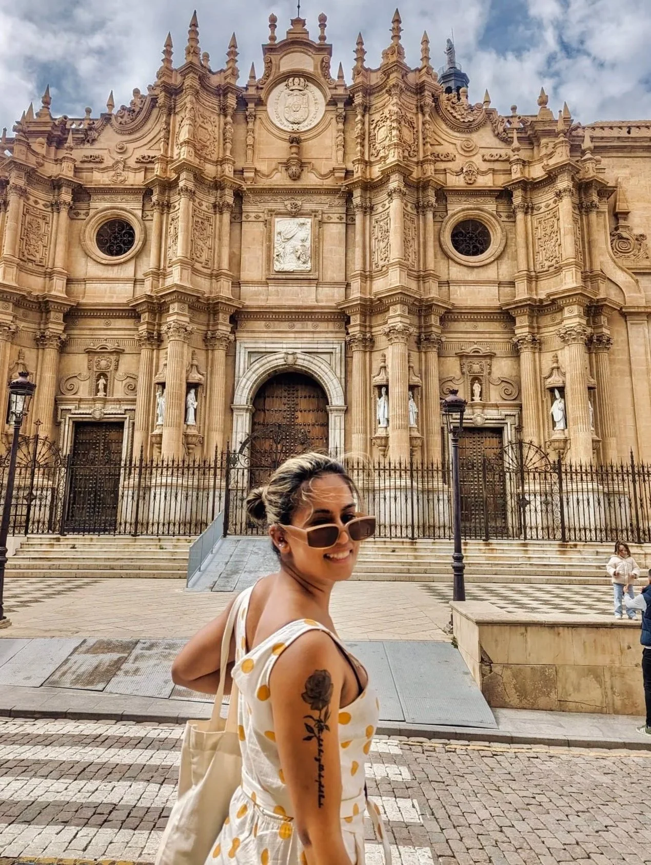 Rose overlooking her shoulder with a background of a beautiful church in a small village in spain