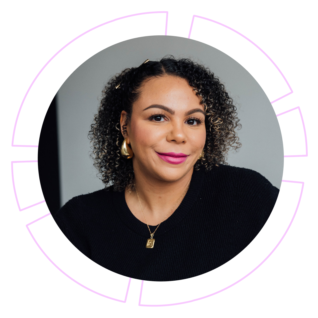 Portrait of a woman with curly dark hair, wearing a black top, gold earrings, a gold necklace with a pendant, and pink lipstick, smiling at the camera.