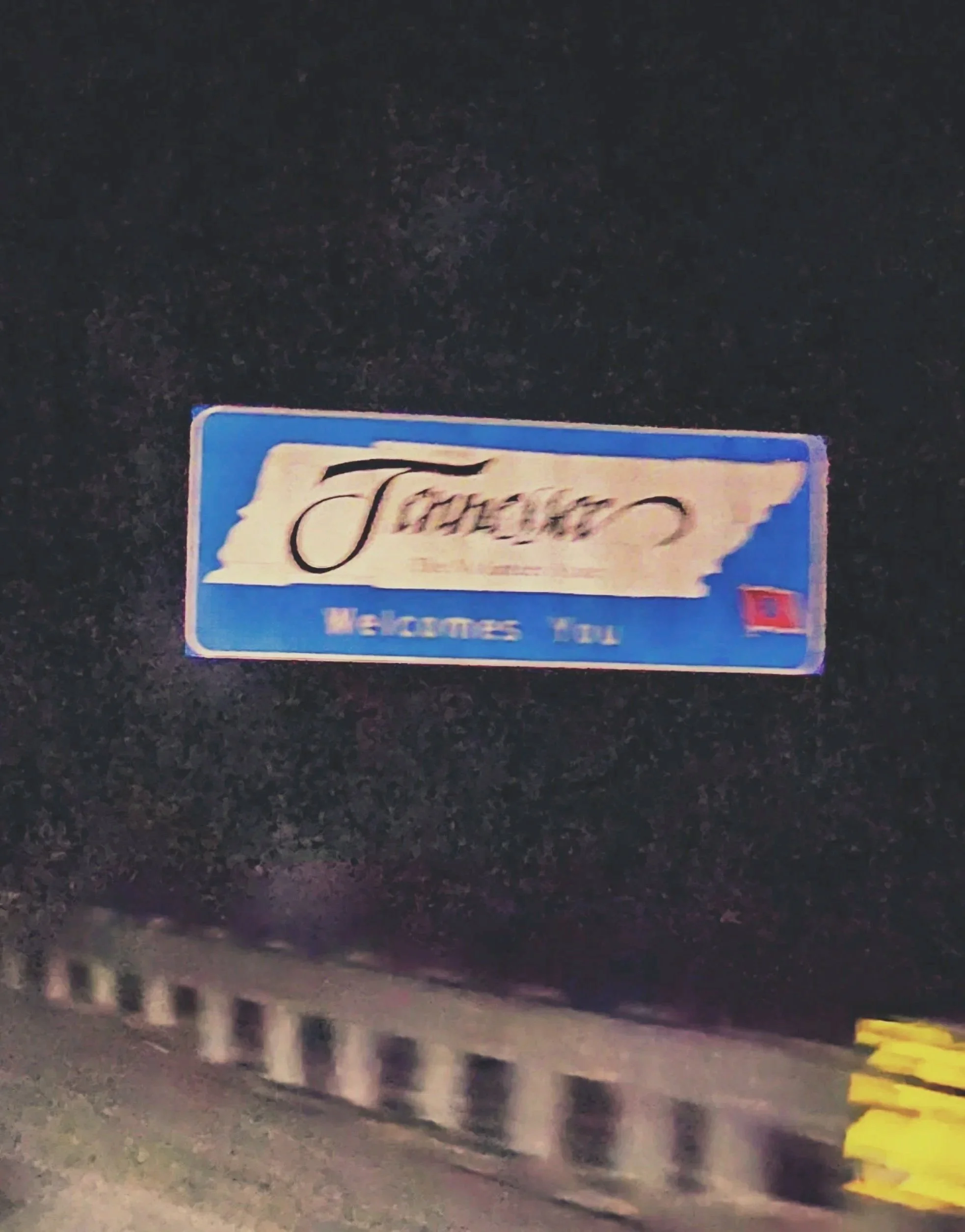 Close-up of a welcome sign that says "Welcome You" against a dark background.