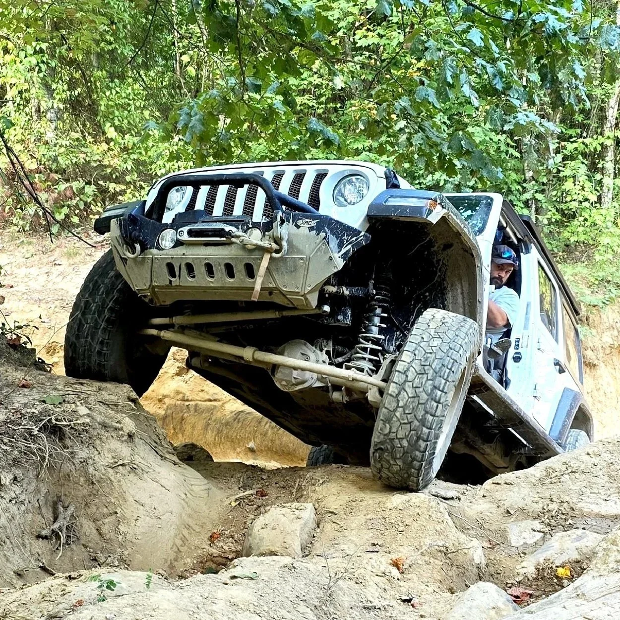 An off-road vehicle, possibly a Jeep, driving on a rocky trail with a person looking out from the passenger side.