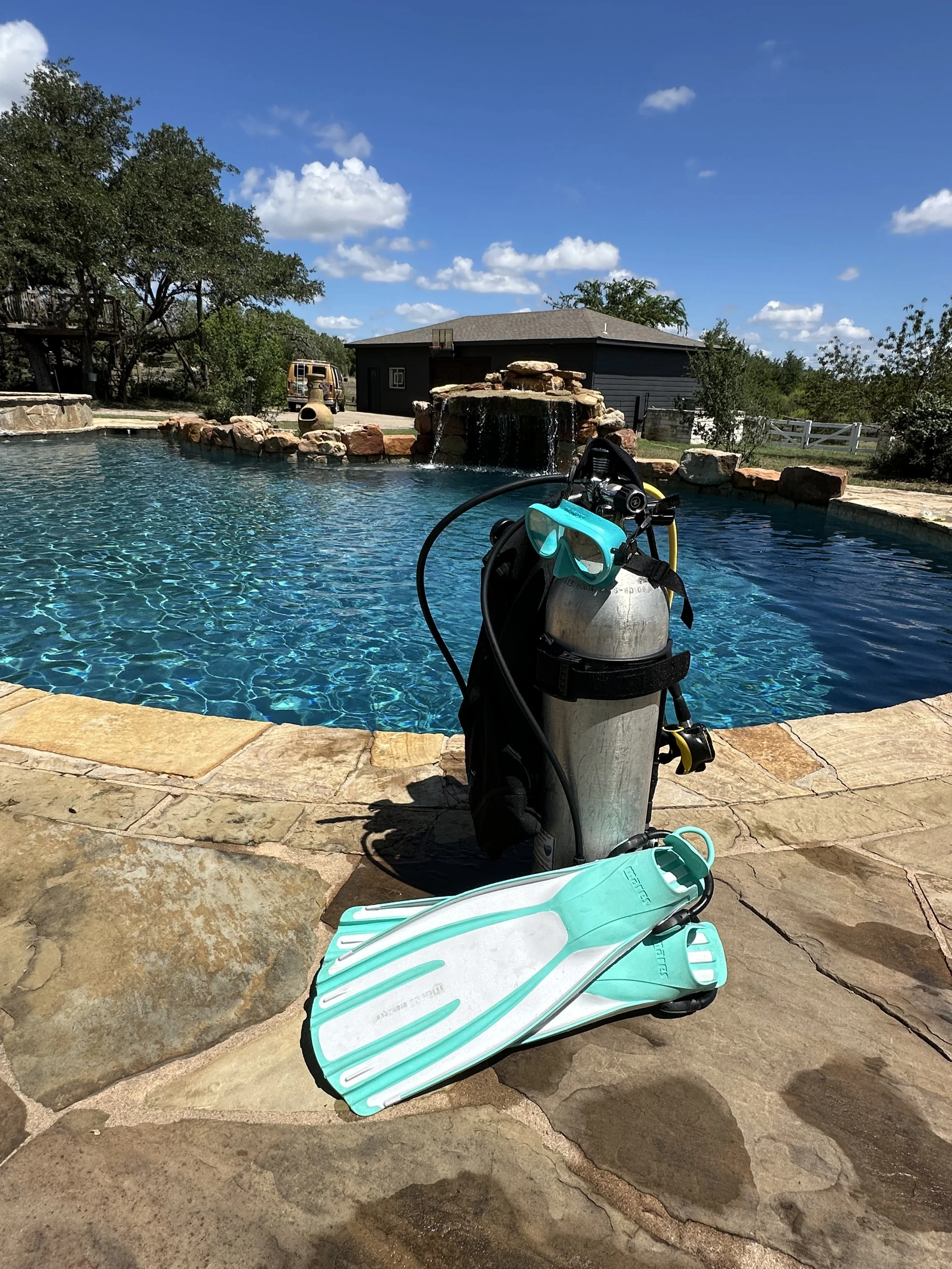 Scuba diving gear besides a backyard pool, reflecting Chelsea Stobaugh's passion for diving.