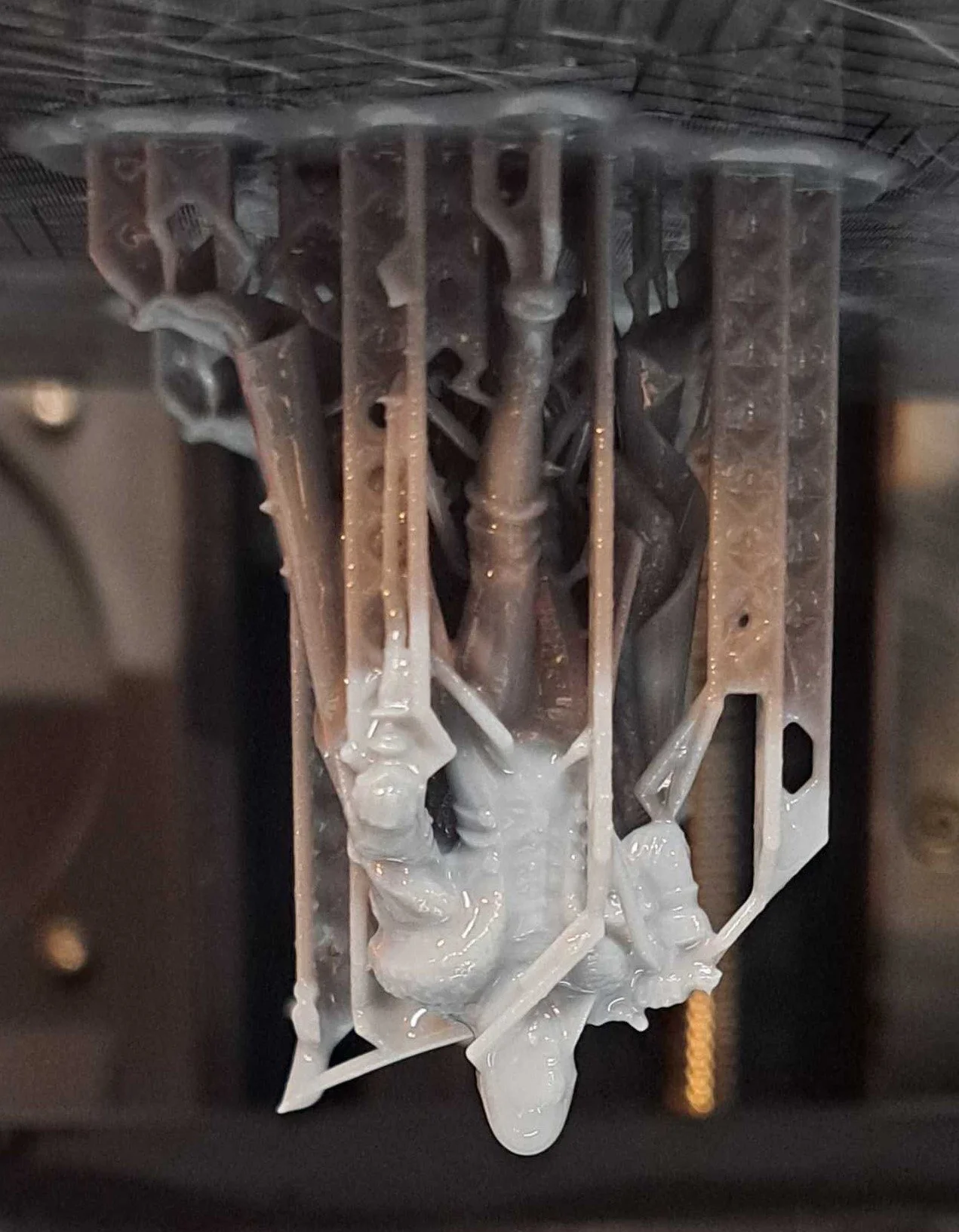 A close-up view of a mechanical component with several metal parts, some covered in white lubricant or grease, attached to a metal frame.