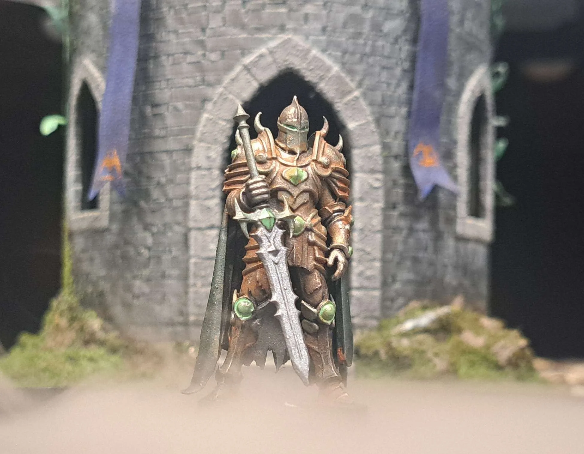 Miniature armored knight figure with a sword, standing in front of a stone castle facade with flags and moss.